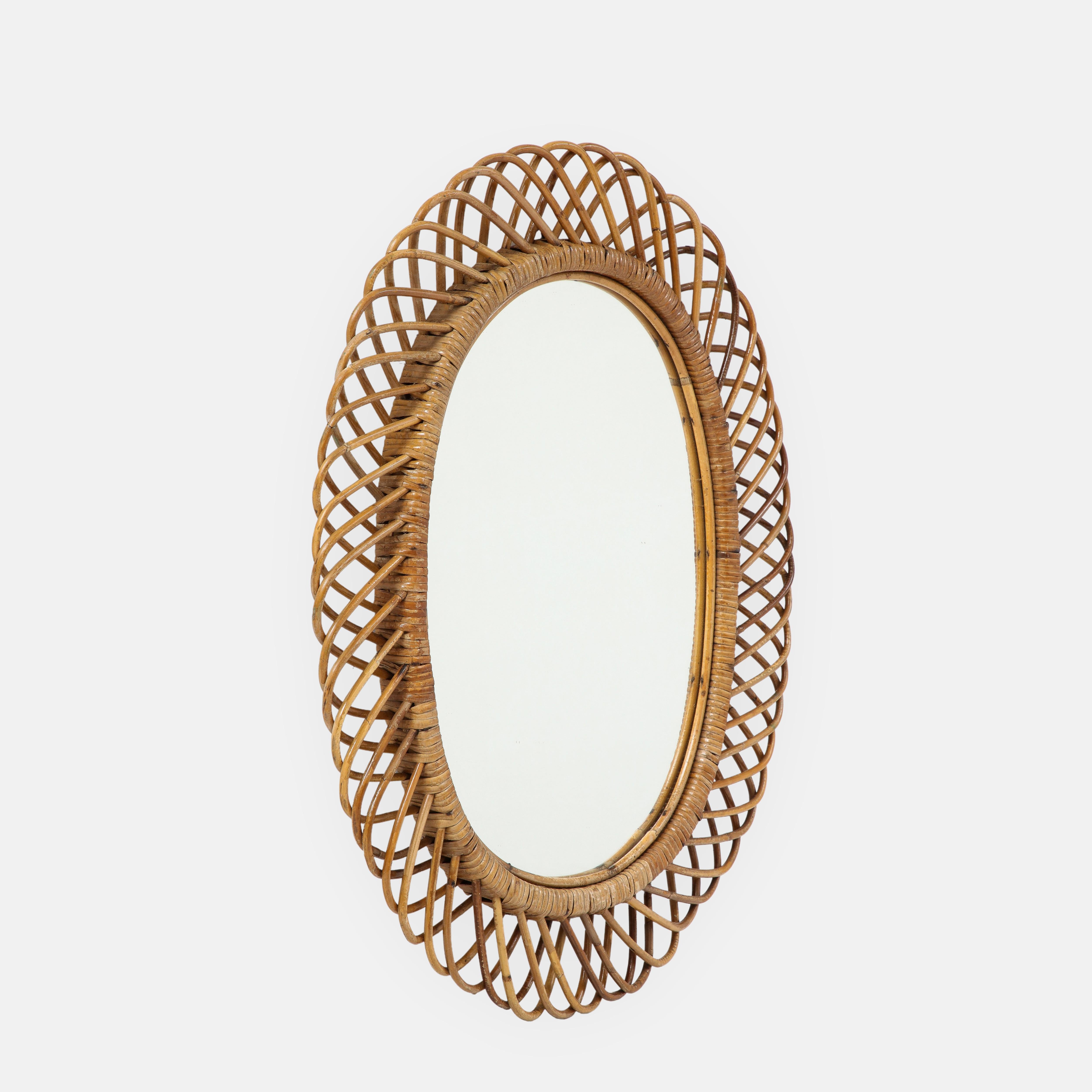 Franco Albini for Bonacina oval bamboo and rattan wall mirror, Italy, 1950s. This chic and iconic Italian mid-century mirror is intricately hand-woven with bamboo and rattan, then stained and lacquered. Original red velvet on backside of mirror.