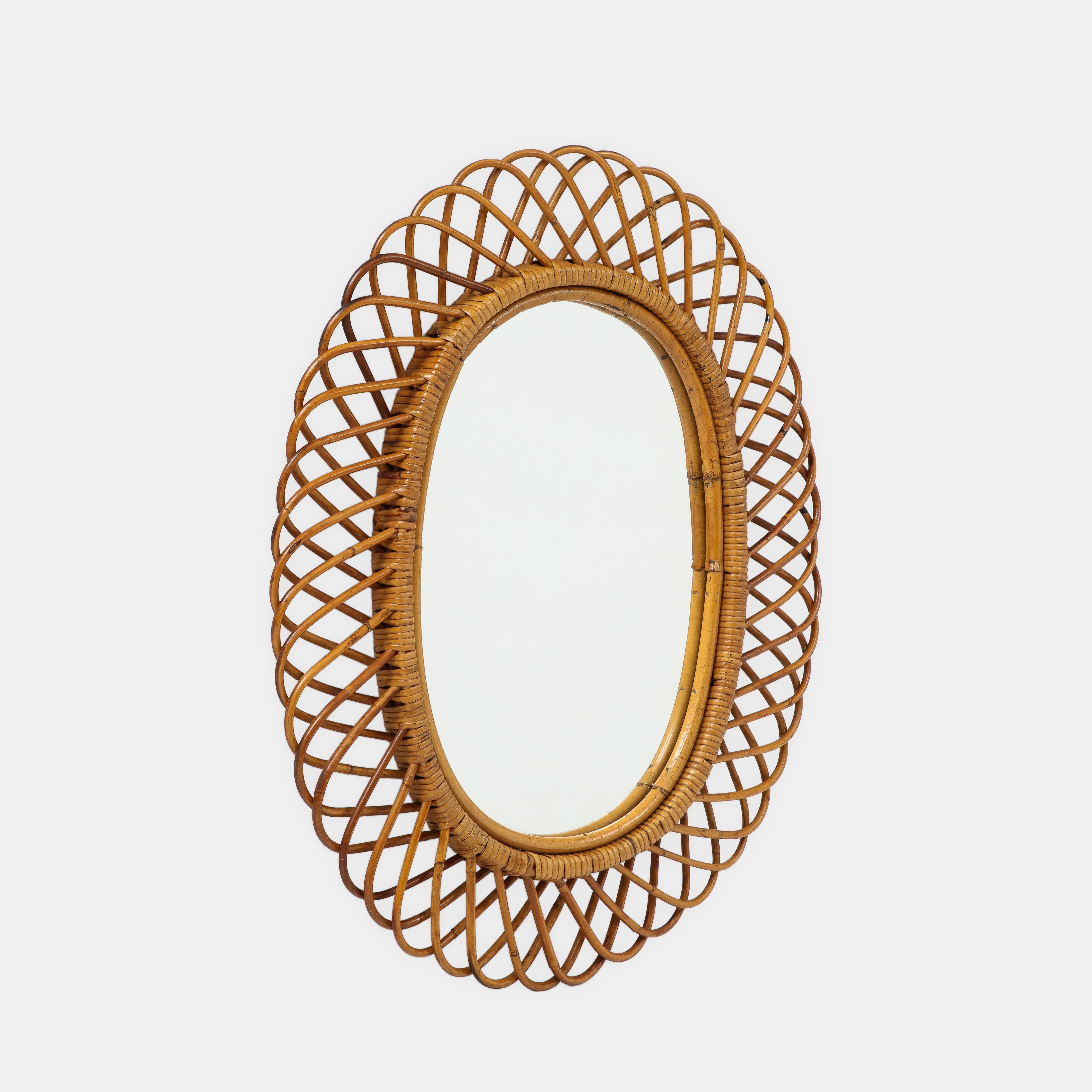 Franco Albini for Bonacina oval bamboo and rattan wall mirror, Italy, 1950s. This chic and iconic Italian mid-century mirror is intricately hand-woven with bamboo and rattan, then stained and lacquered. Original red velvet on backside of mirror.