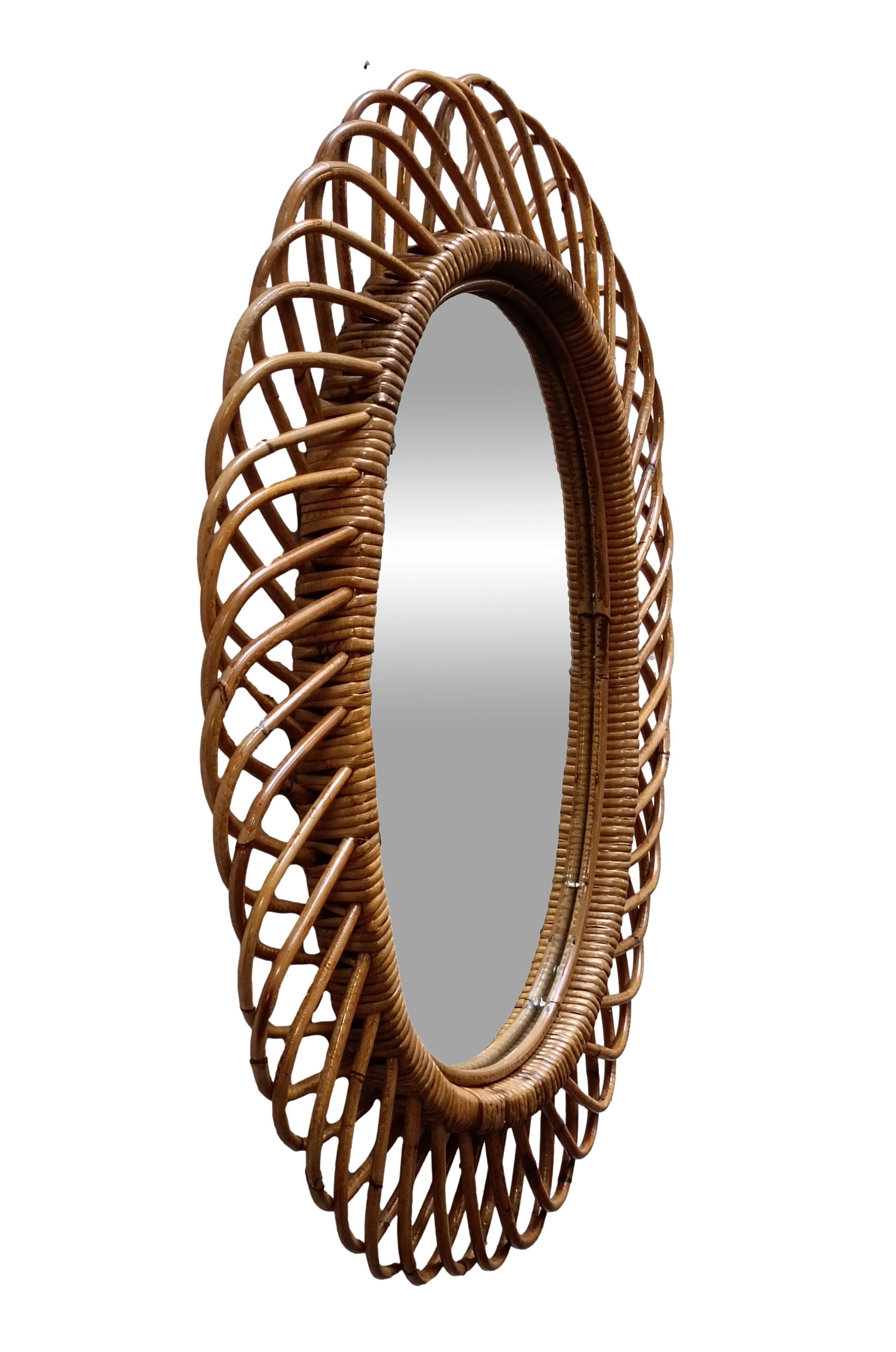 Specchio da parete in rattan italiano (circa anni '60). Lo specchio presenta un complesso intreccio di rattan in una serie di proiezioni a ferro di cavallo sul bordo della cornice. Il rattan presenta una bella patina invecchiata; il vetro è intatto.
