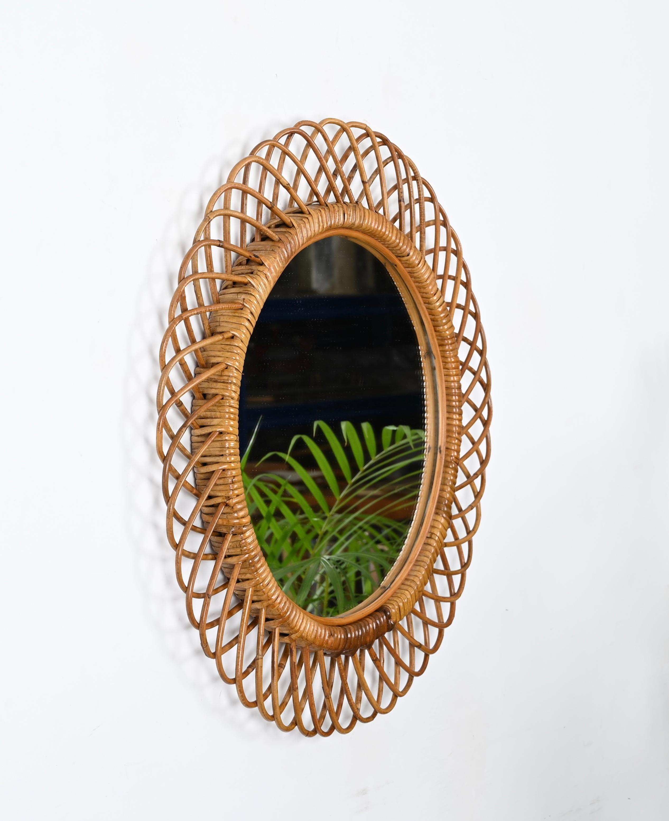 Fantastic midcentury French Riviera style round mirror in curved rattan, bamboo and hand-woven wicker. This stunning piece is attributed to the mastery of Franco Albini and was produced in Italy during the 1960s.

The mirror frame is decorated with