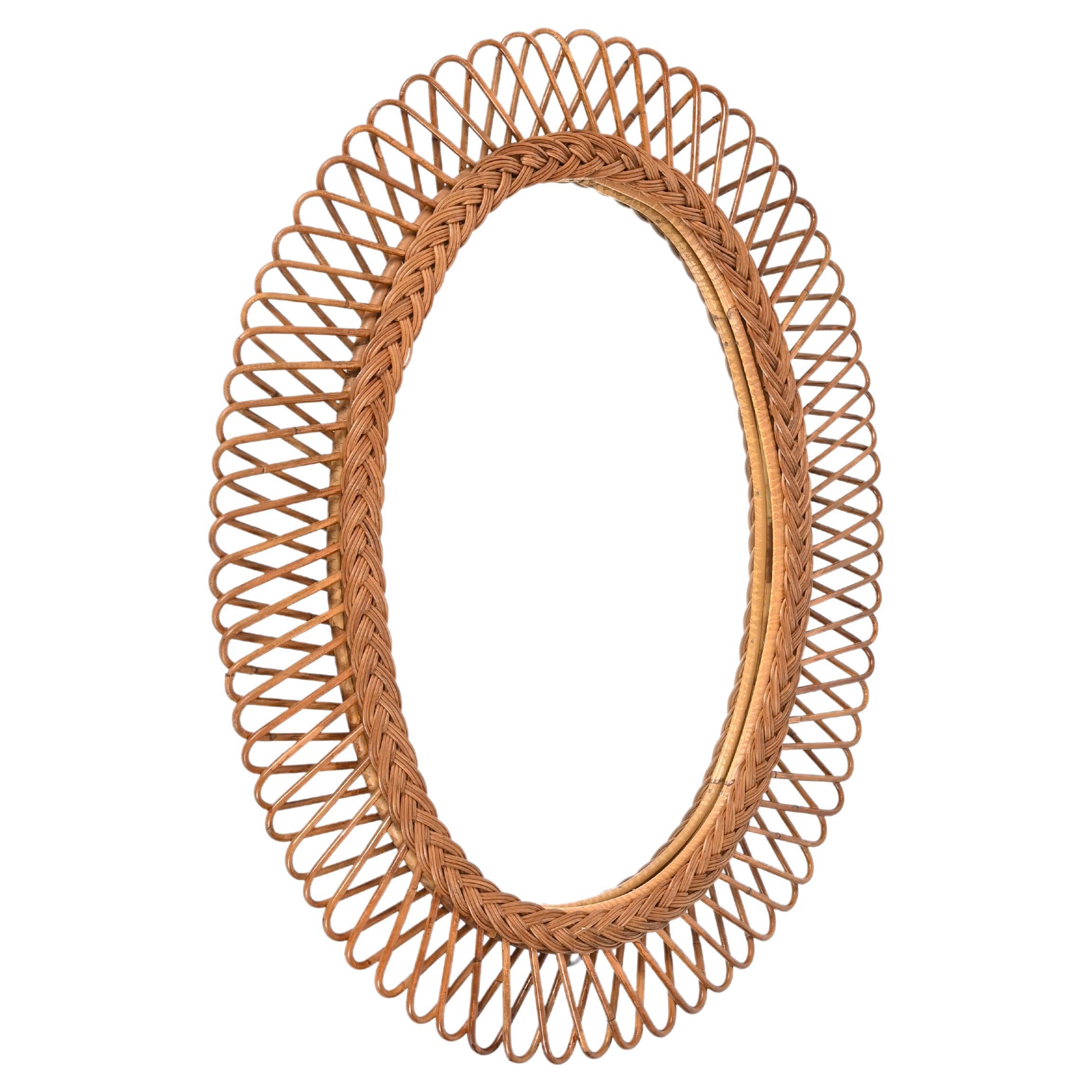 Fantastic Mid-Century French Riviera style oval mirror in curved rattan bamboo and wicker. This marvellous mirror was designed by Franco Albine in Italy during the 1970s. 

This stunning mirror has a double oval frame, enriched by gorgeous curved