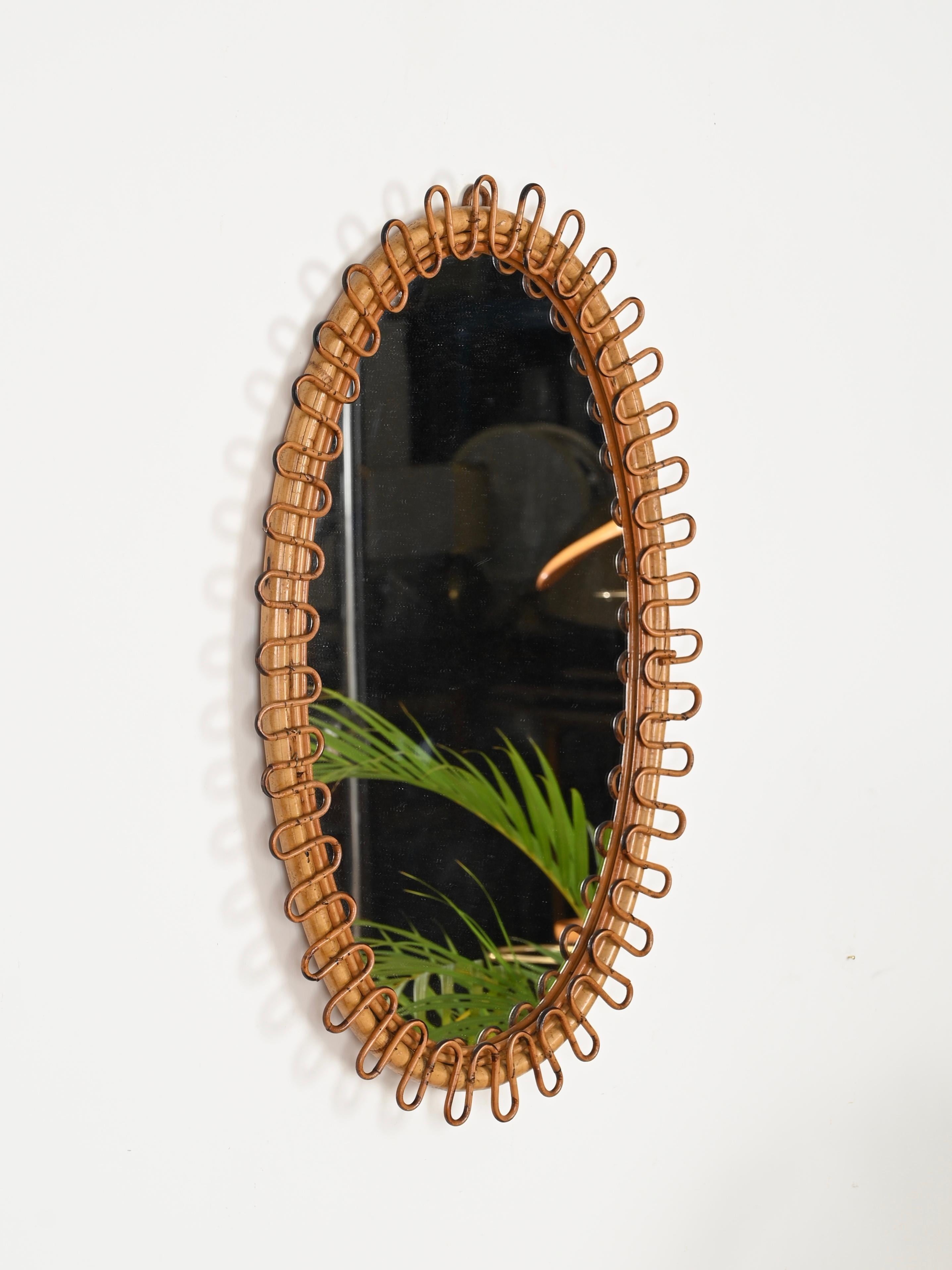 Wonderful Mid-Century French Riviera style oval mirro fully made in curved rattan and bamboo. The design of this delightful organic mirror is attributed to the mastery of Franco Albini and was produced in Italy during the 1960s.

This stylish mirror