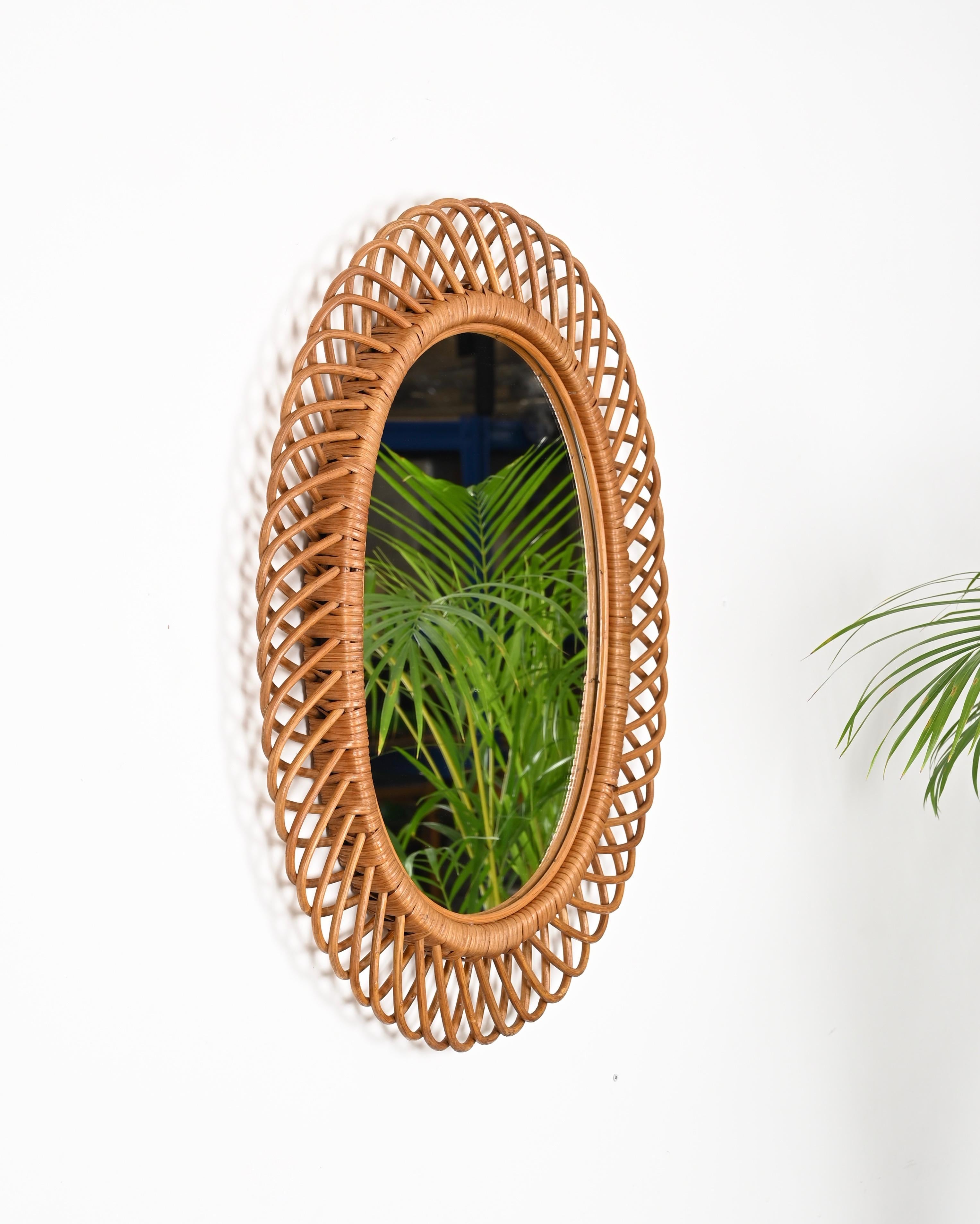 Marvelous French Riviera style oval mirror fully made in curved rattan, bamboo and woven wicker. This lovely mirror was designed by Franco Albini in Italy during the 1960s. 

This charming decorative mirror was fully hand-crafted with perfect