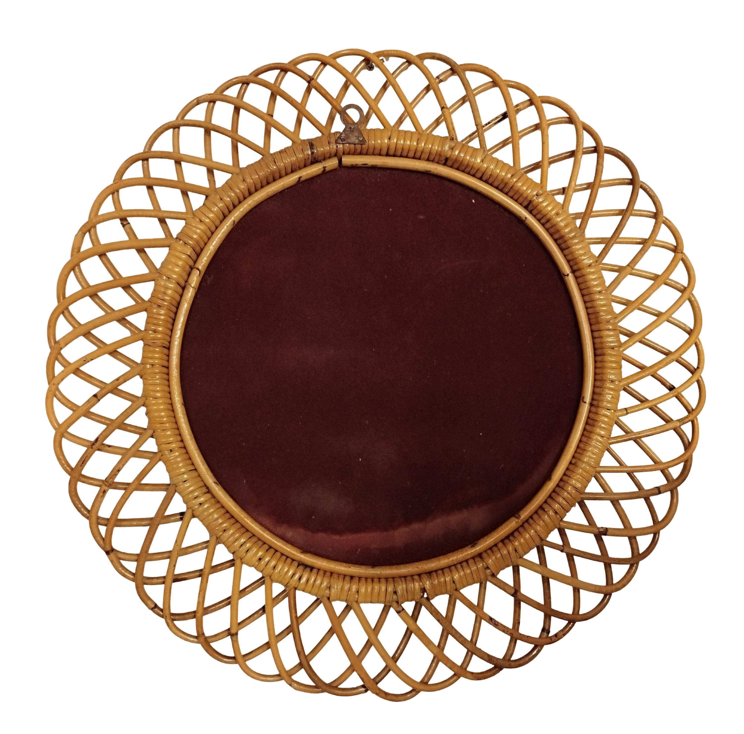Specchio da parete in rattan italiano  di Franco Albini. Lo specchio presenta un complesso intreccio di rattan in una serie di proiezioni a ferro di cavallo sul bordo della cornice. Il rattan presenta una bella patina invecchiata. Presenta alcuni