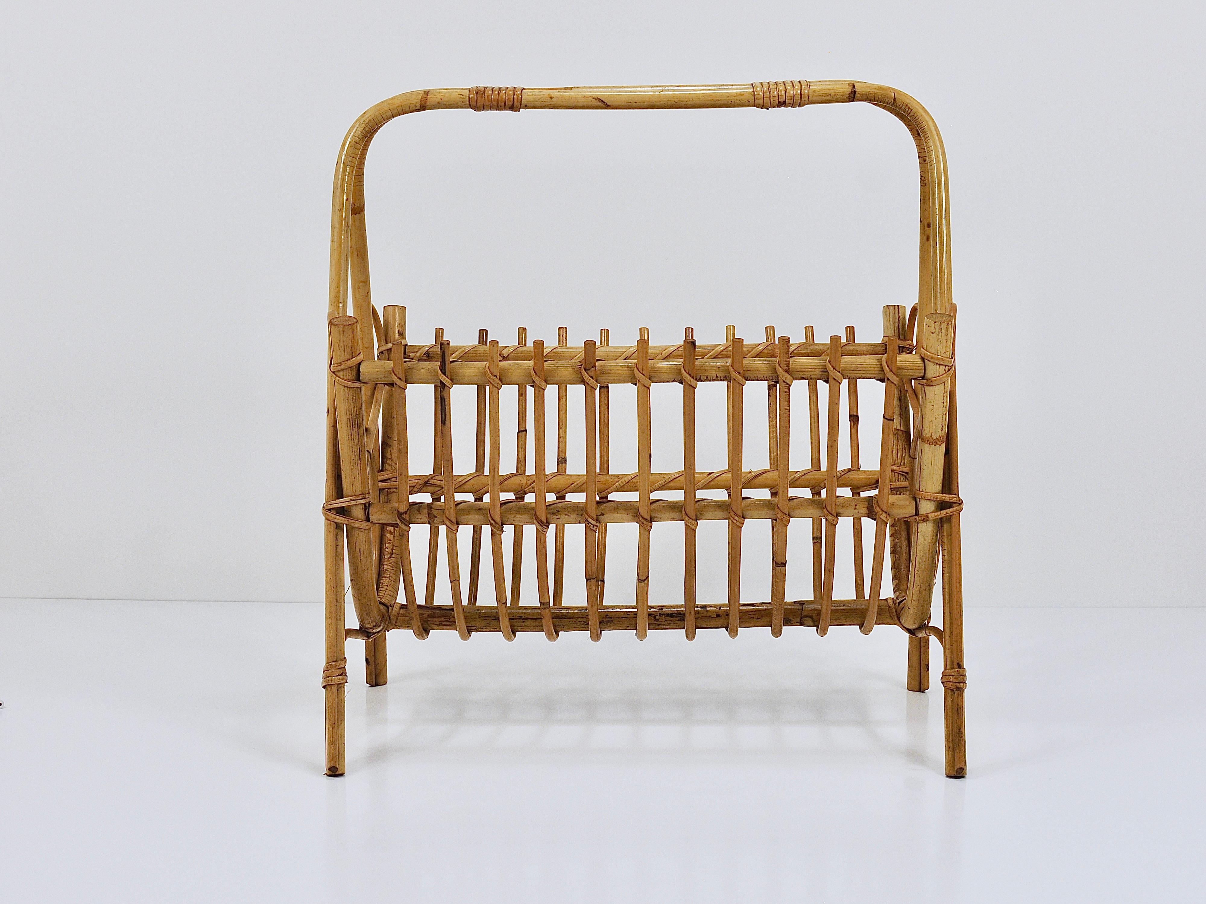 A chic French Riviera style midcentury modern bamboo rattan newspaper rack / magazine holder from the 1950s/1960s. Traditionally handmade of bent bamboo and rattan / cane / wicker. A decorative, vintage piece of furniture, which can be also used as