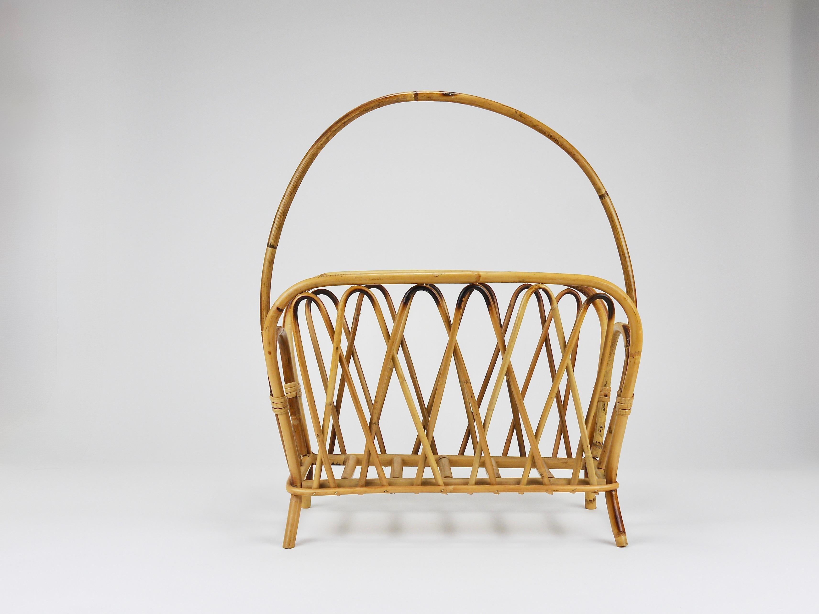 A chic French Riviera–style midcentury modern bamboo and rattan newspaper rack / magazine holder from the 1970s. Handcrafted from bent bamboo and rattan / cane / wicker. A decorative vintage piece of furniture that, due to its size, can also be used
