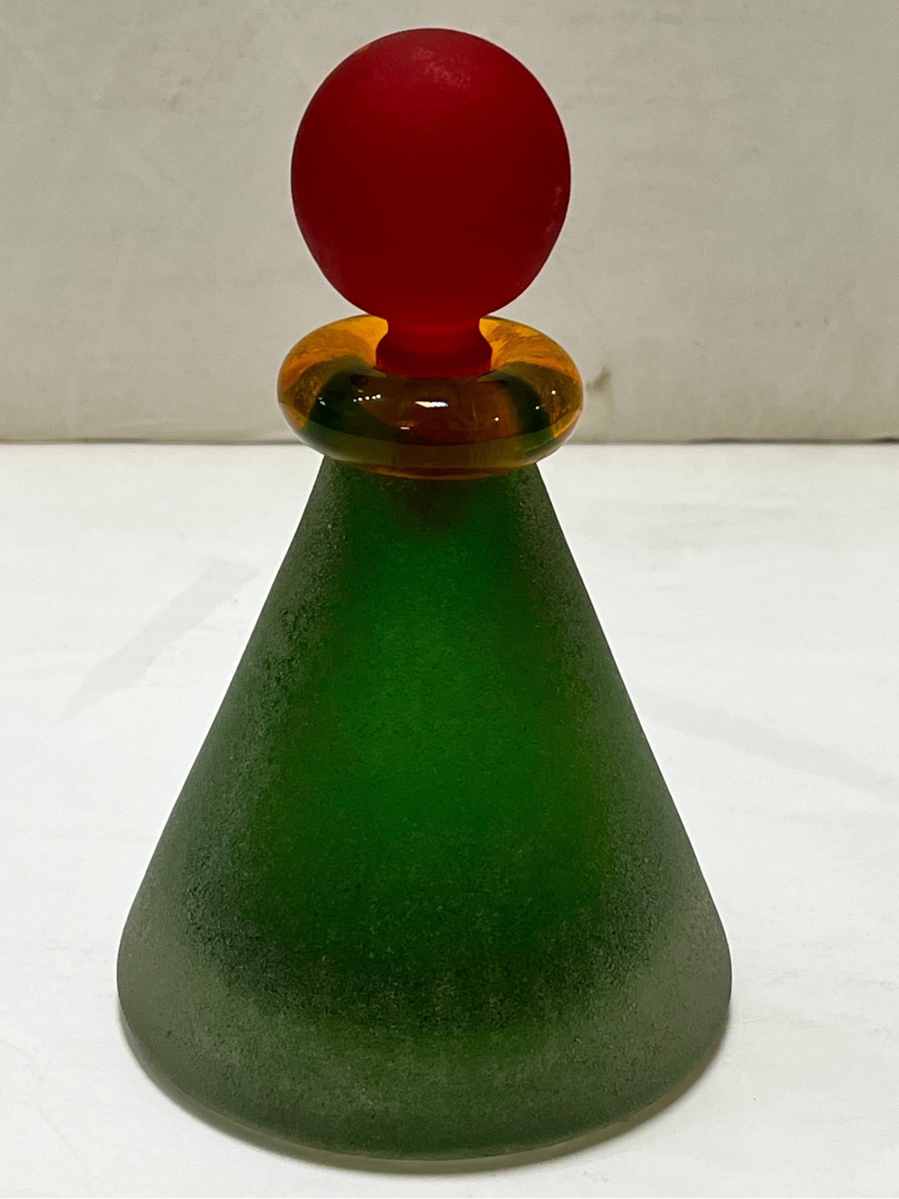 A vintage circa 1980's or 1990's Memphis style perfume bottle by Italian glass artisan Franco Moretti. This scavo style finish vessel is conical in shape with strong color blocking design - the green base, yellow neck and red stopper. The strong