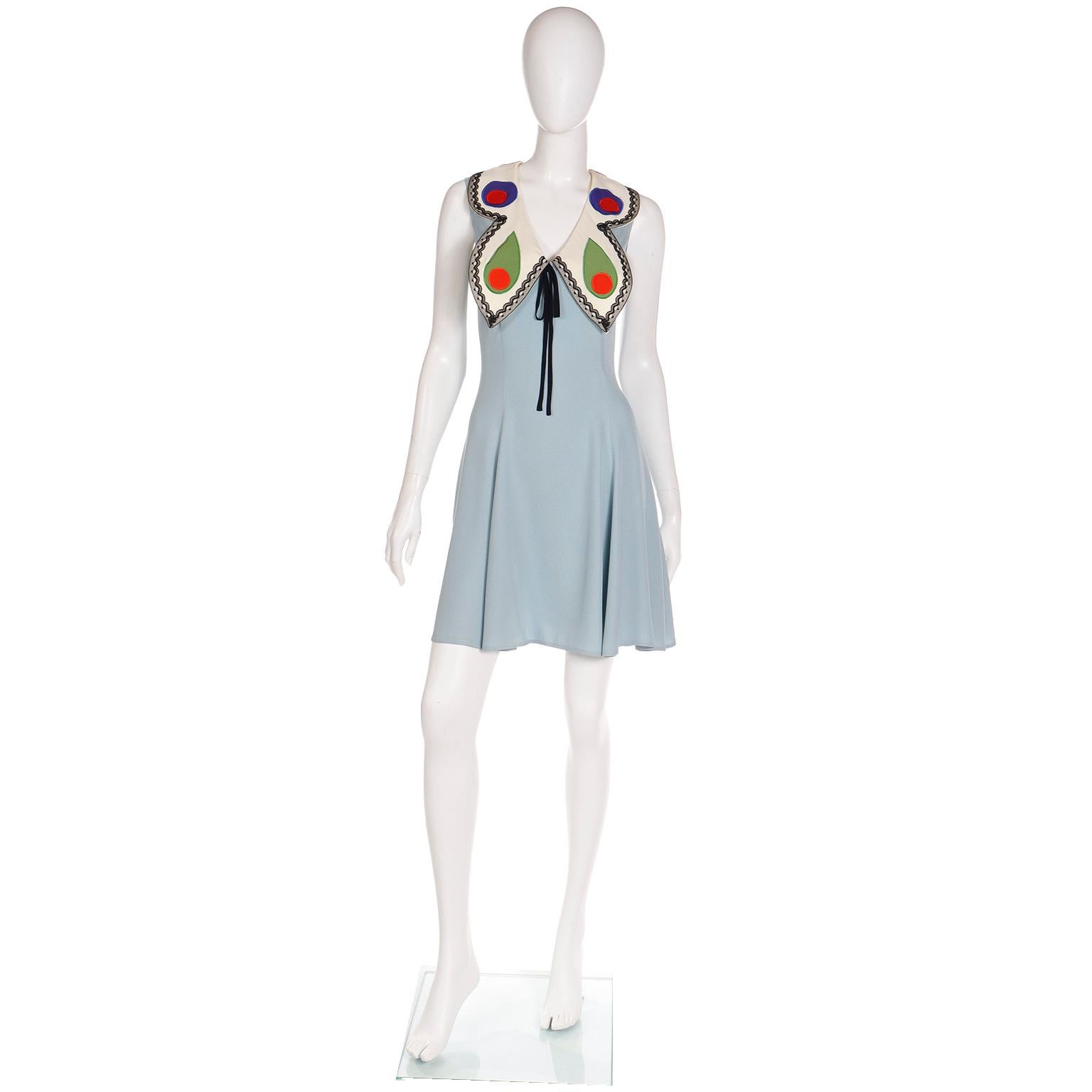 This is a 1990s Franco Moschino sleeveless blue dress with a bold butterfly collar. Franco Moschino had a lot of symbols and icons that he repeatedly used and the butterfly is one that he used often. The dress is in 100% silk and the butterfly wings
