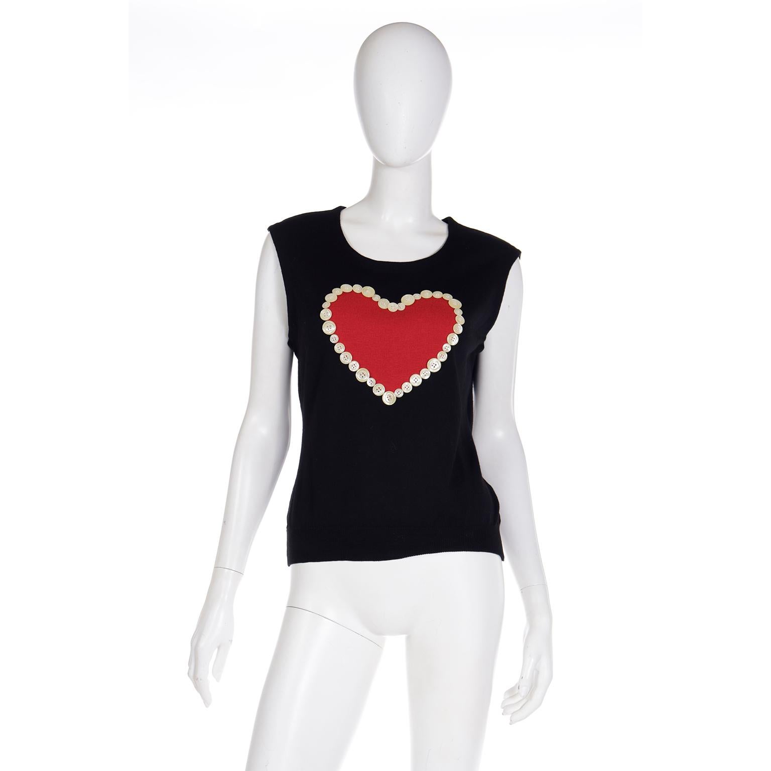 This early Cheap and Chic by Moschino black wool knit sleeveless top features a large red heart on the front that is surrounded by little buttons! This fun piece can be worn as a top or a vest. Franco Moschino often used hearts as symbols in his