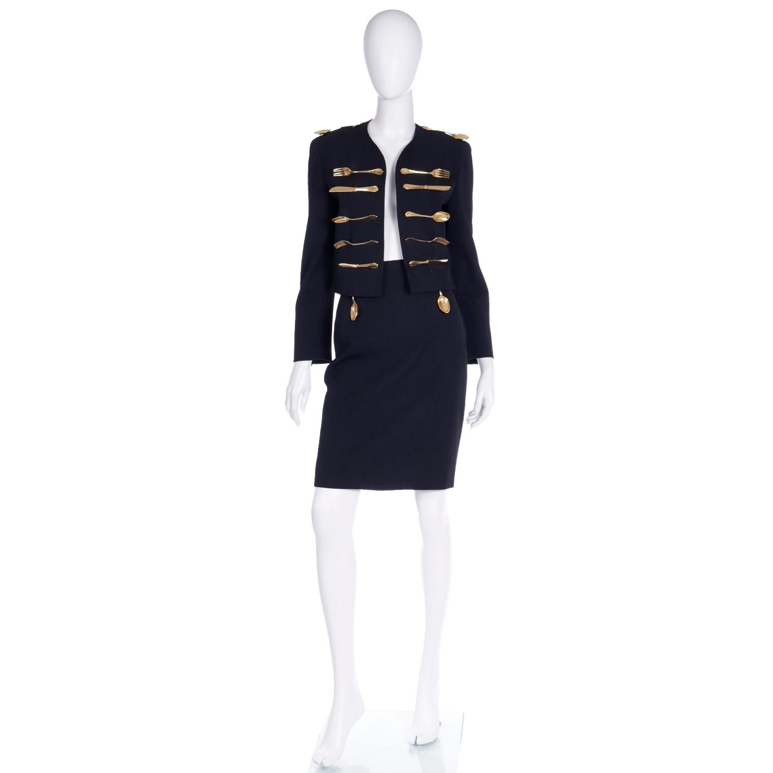 This iconic Franco Moschino 2 piece suit is in the Met's costume collection. This dinner suit outfit includes a cropped open front jacket and a slim skirt. They are embellished with gold tone lightweight metal forks, knives and spoons. Moschino