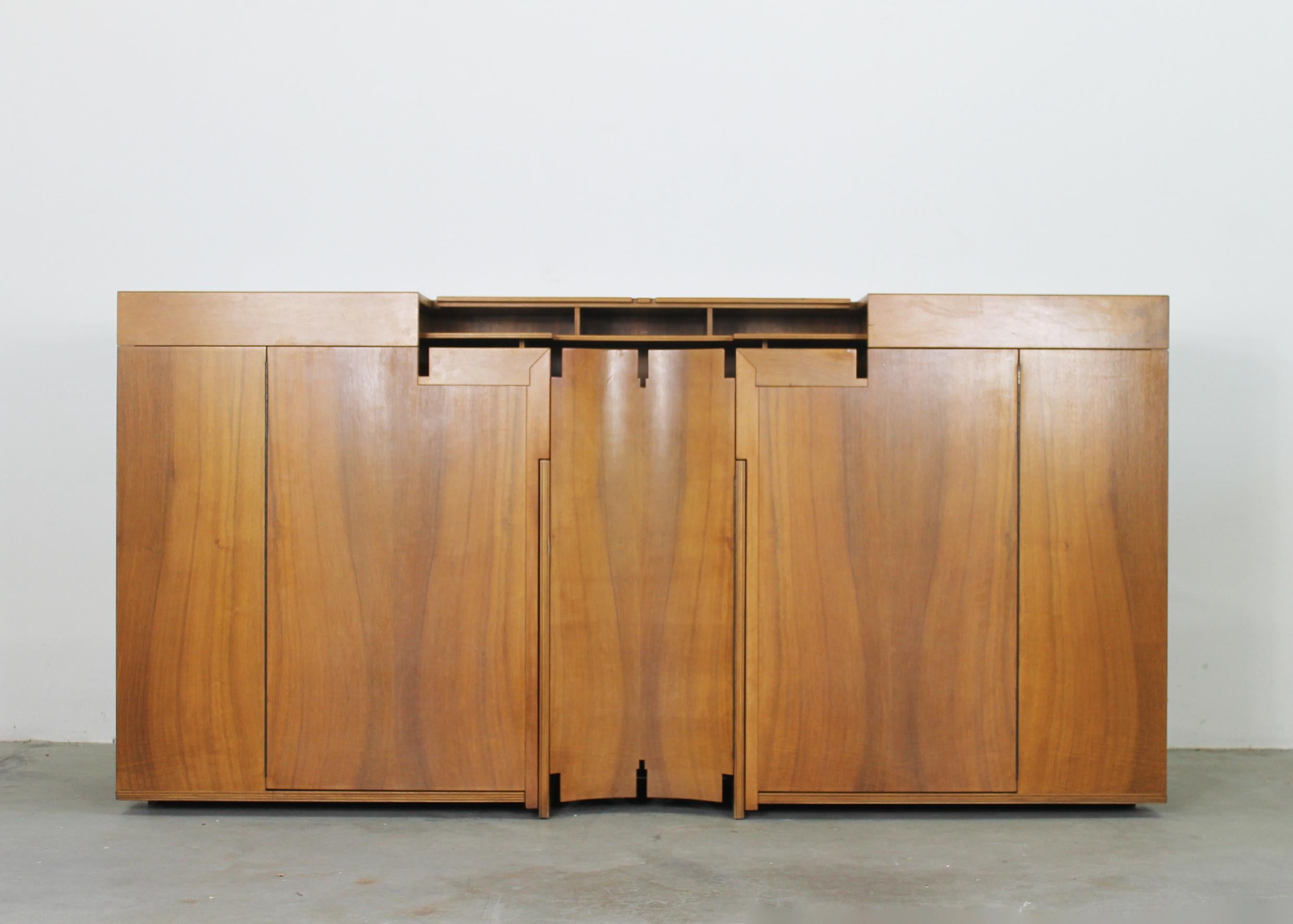 Sideboard in walnut wood from the Scaligera series designed by Franco Poli for Bernini in the 1980s. 
The sideboard presents doors with inner shelves, drawers, and flap-opening compartments on the top.
The high carpentry on which this sideboard was