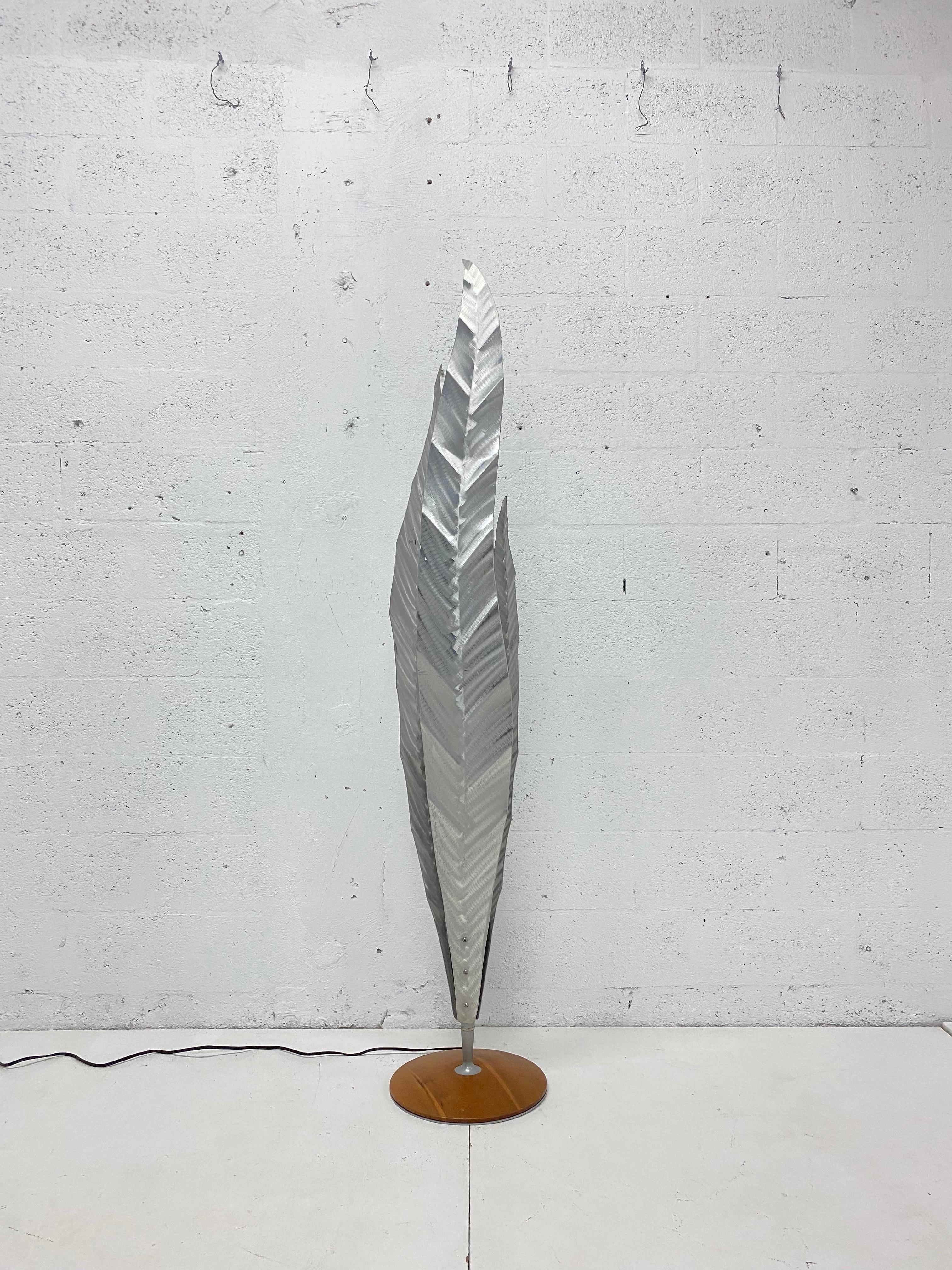 Hand crafted aluminum floor lamp with three vertical aluminum leaves welded to a steel rod and attached to a wood base. The E27 lamp is internal and can use up to a 100W bulb. The Aloe Piantana lamp was designed by Franco Zavarise for Zava Luce