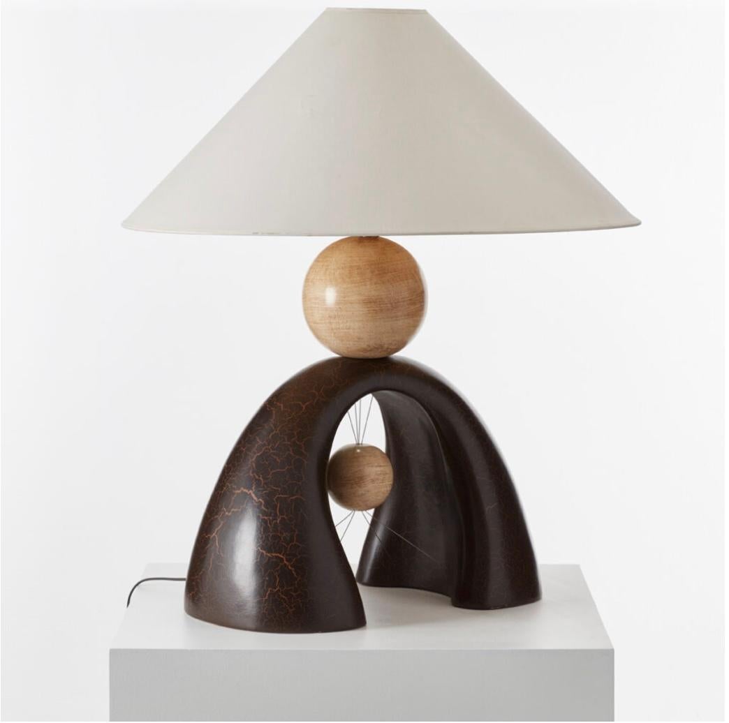 En équilibre, François Châtain joue habilement avec la dynamique. La lampe de table semble avoir une boule en bois qui flotte délicatement entre les périmètres de la lampe.  Comme son nom l'indique, la lampe galet joue avec l'idée de galets empilés