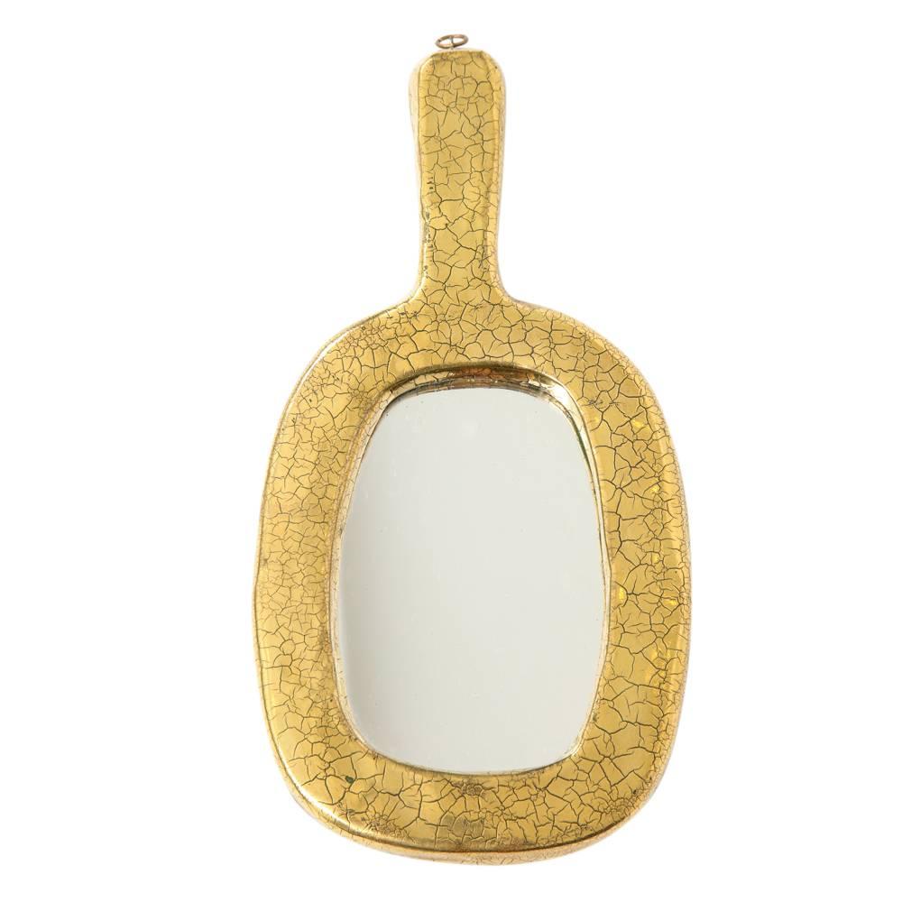 Mithé Espelt gold ceramic mirror crackle glaze, France, 1970s. Petite vanity form mirror in gold crackle glaze with felt covered back.
 