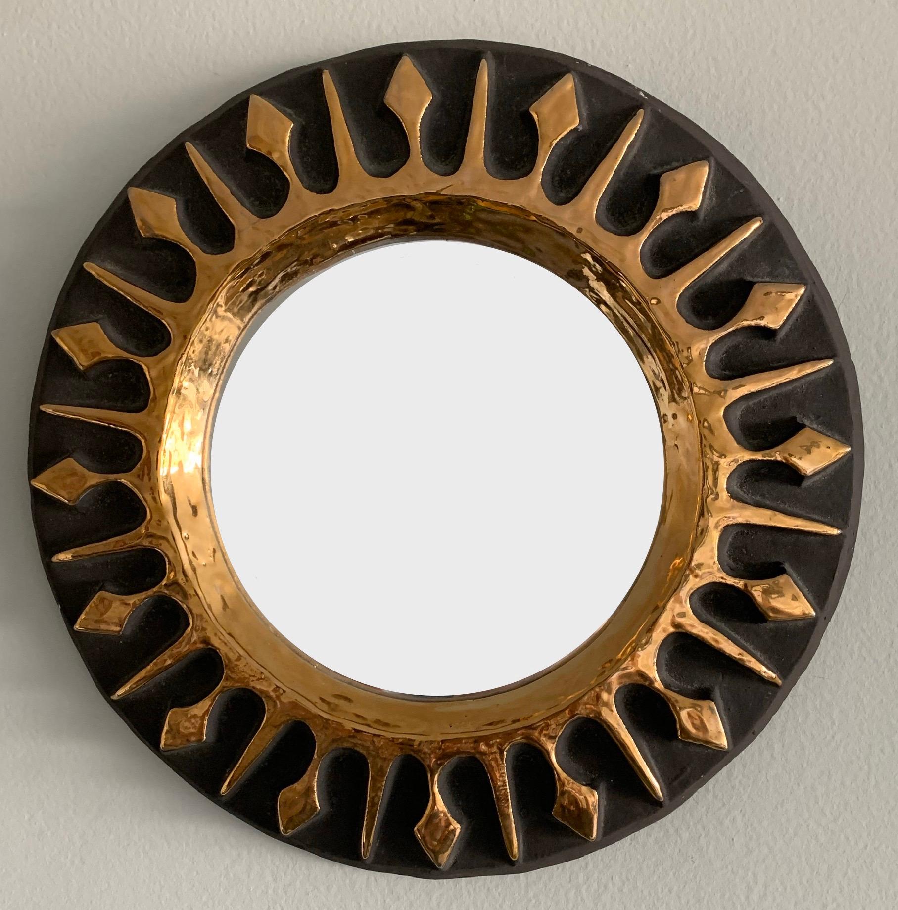 Midcentury French ceramic round mirror by Mithé Espelt. Dark brown glazed finish with hand painted gold gilt sunburst. Backed in green felt with center hook for hanging. Hanging hardware not included.