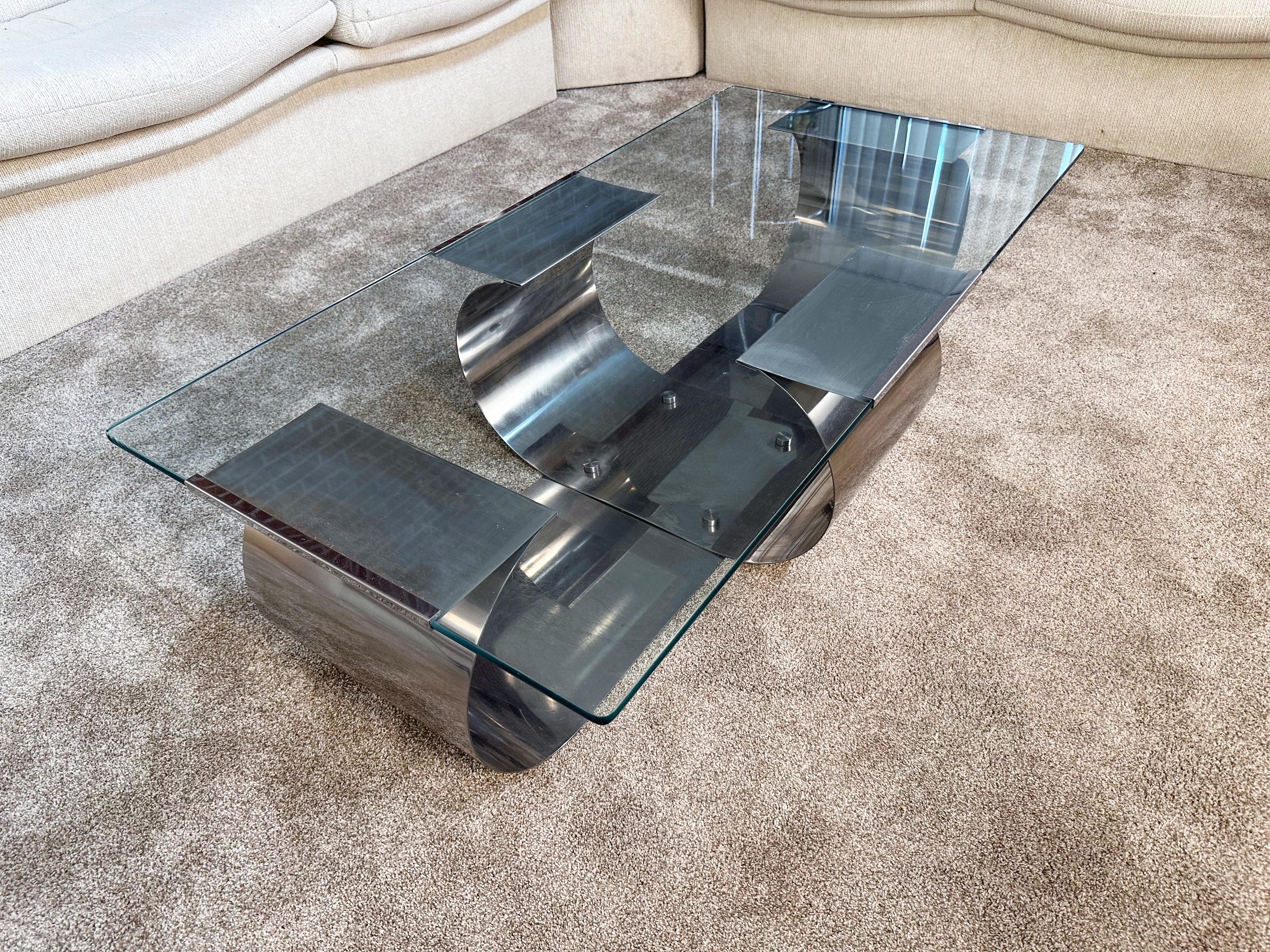 A stunning example of French modernist design, this coffee table designed by François Monnet for Kappa embodies the sleek, sculptural aesthetic of the 1970s. The base, crafted from polished stainless steel, features two elegantly curved, ribbon-like