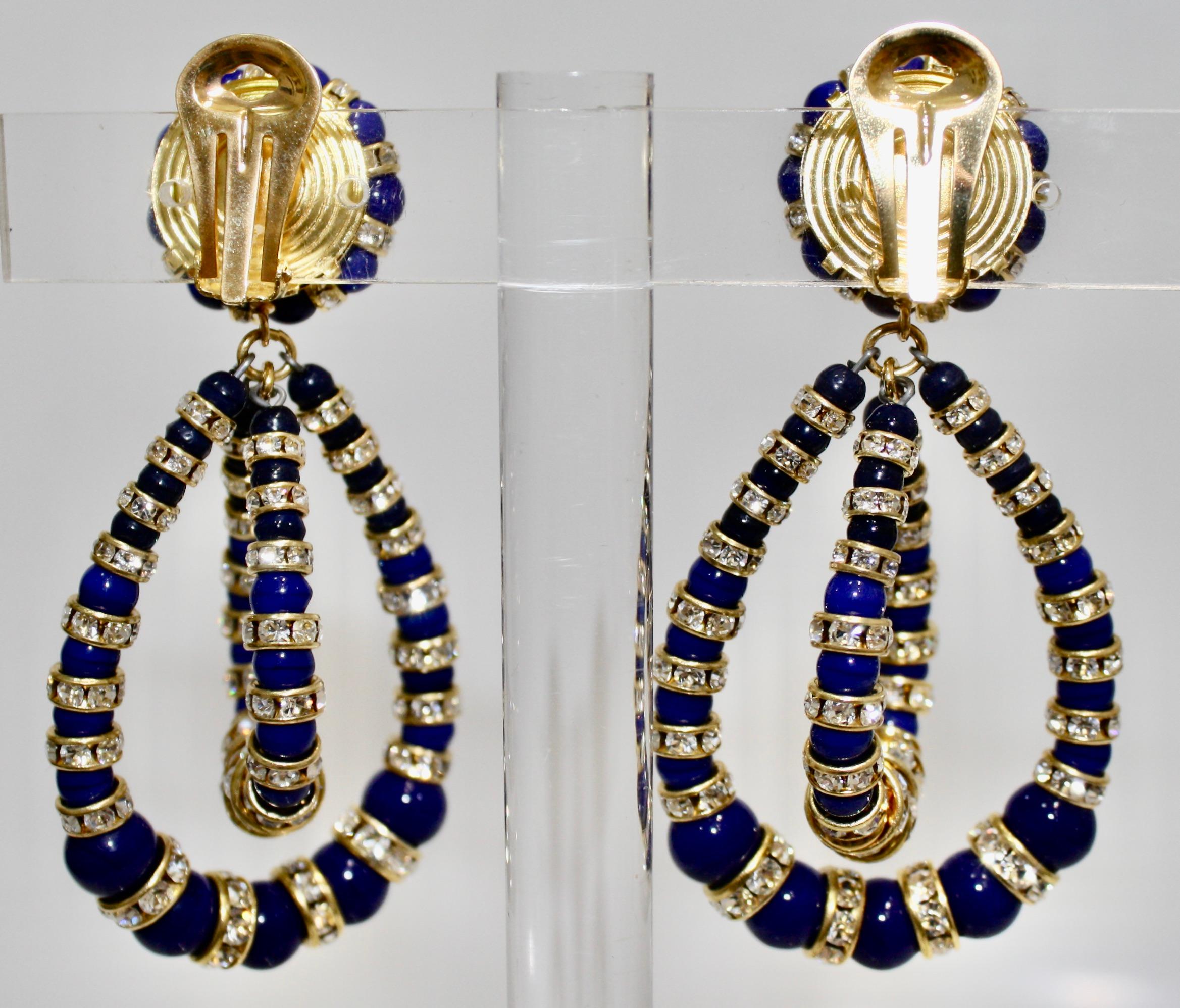 Twisted oval shaped hoops with Lapis colored handmade glass cabochon and Swarovski crystal rondelles on gold.Gilded brass clip earrings.