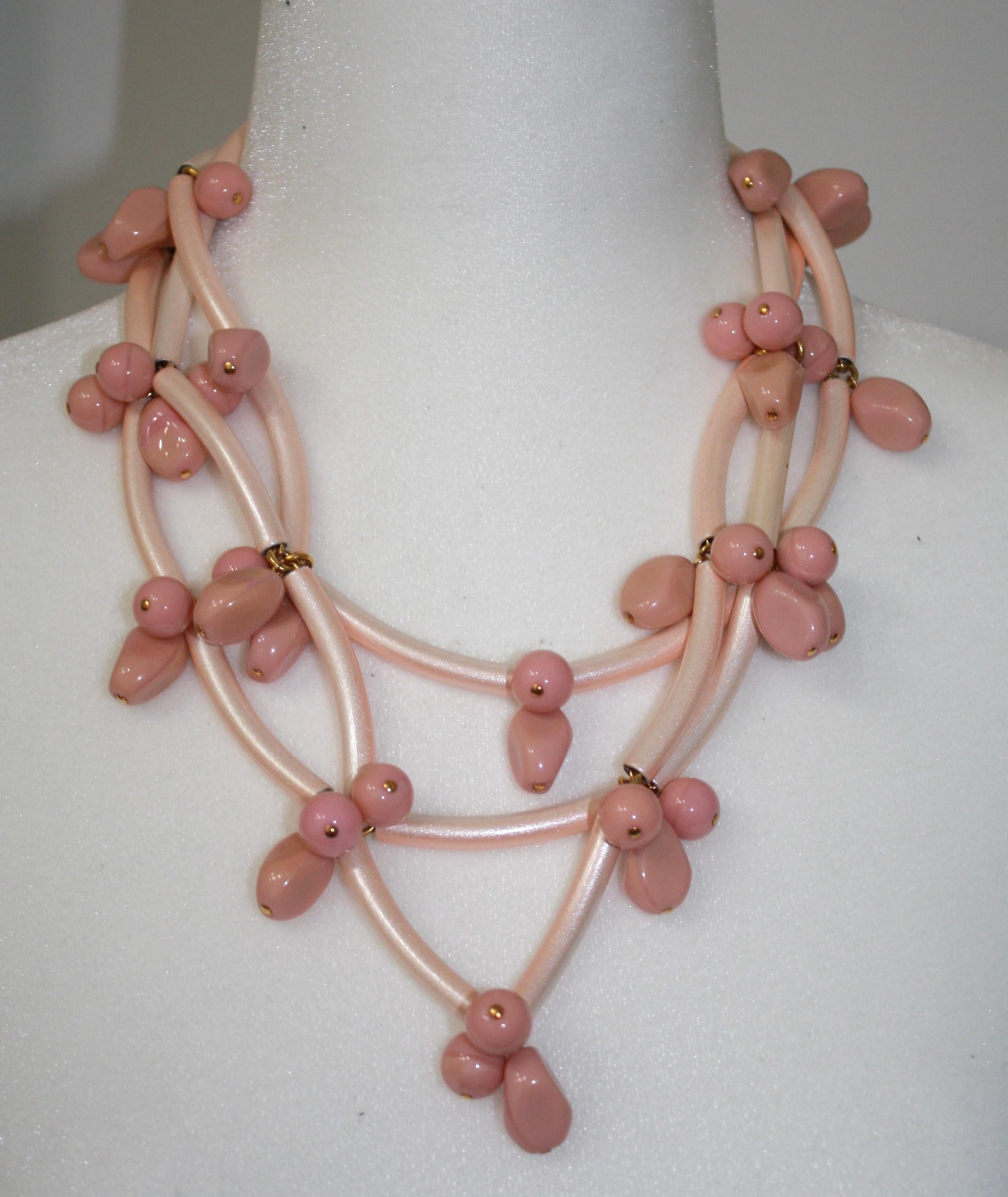 Blush color metallic tubes intertwined with handmade glass beads. Iconic design made in Paris.