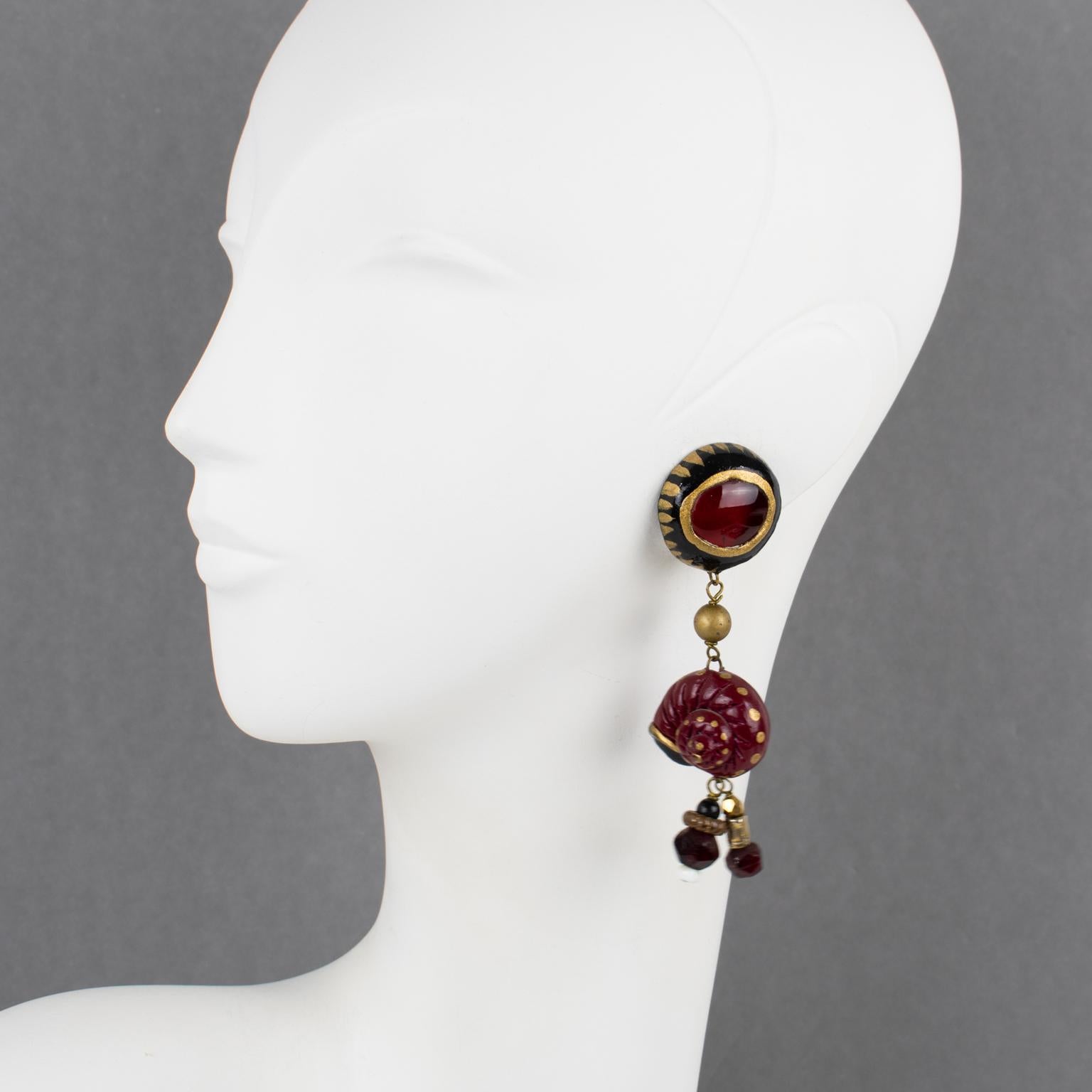 These stunning French designer Francoise Montague clip-on earrings boast a long dimensional shape with hand-made and hand-painted resin elements (big eye and nautilus shell,) complimented with glass beads and drops. The earrings feature black,