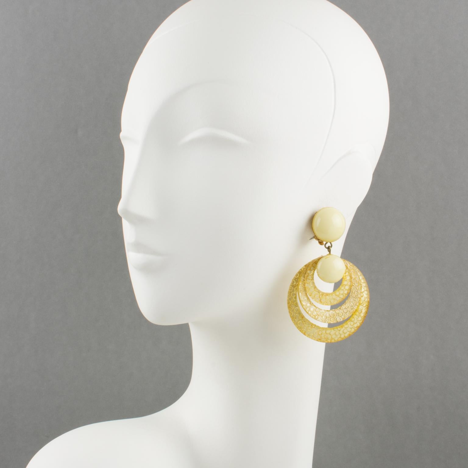 Adorable clip-on earrings, designed and manufactured by Cilea Paris for Francoise Montague. Oversized dangle shape, in light yellow resin featuring graduated rings. The assorted carved and textured patterns are used differently to increase the