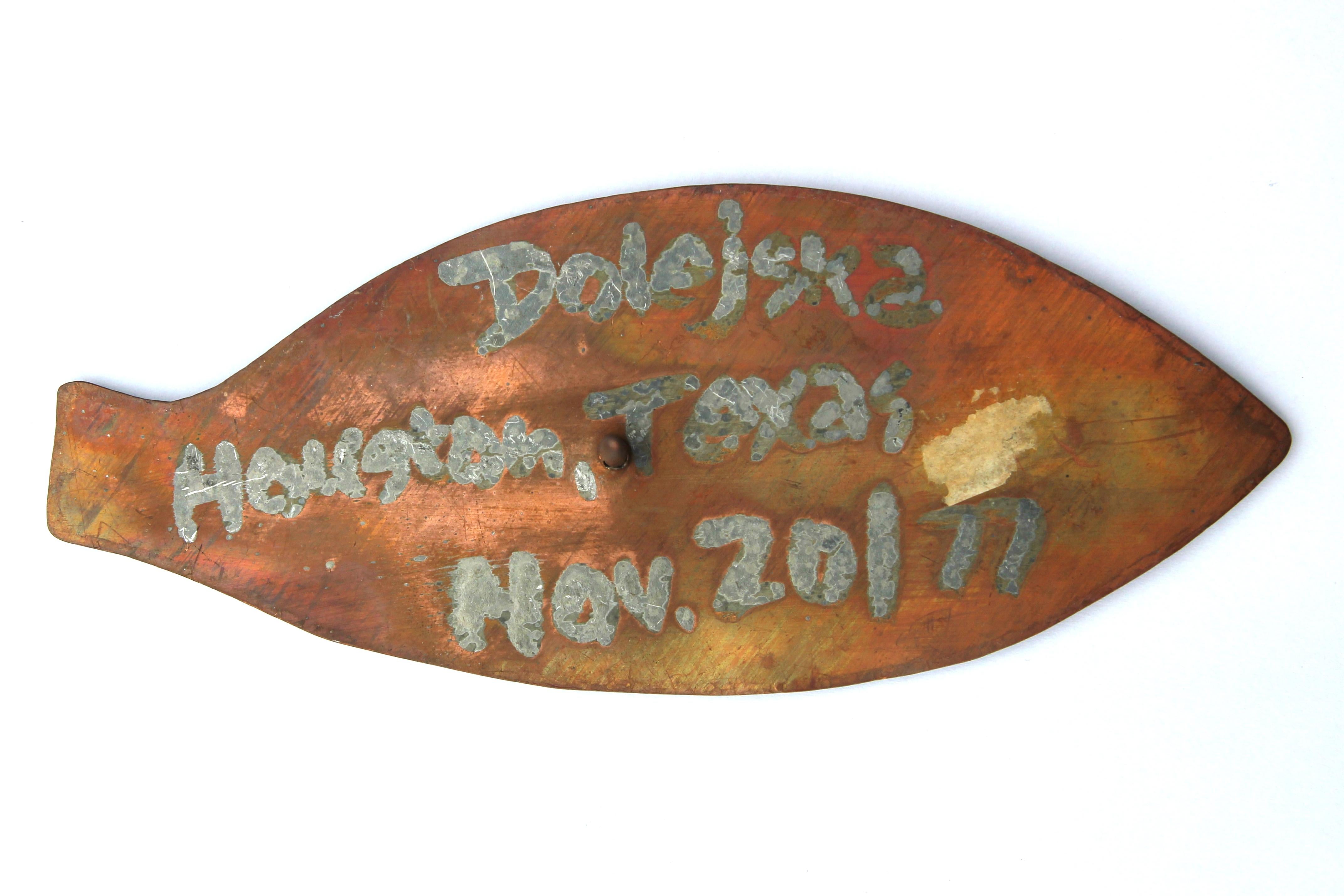 Modern abstract fish sculpture made of copper by Houston, TX artist Frank Dolejska. The work features a rounded fish shape with the words 
