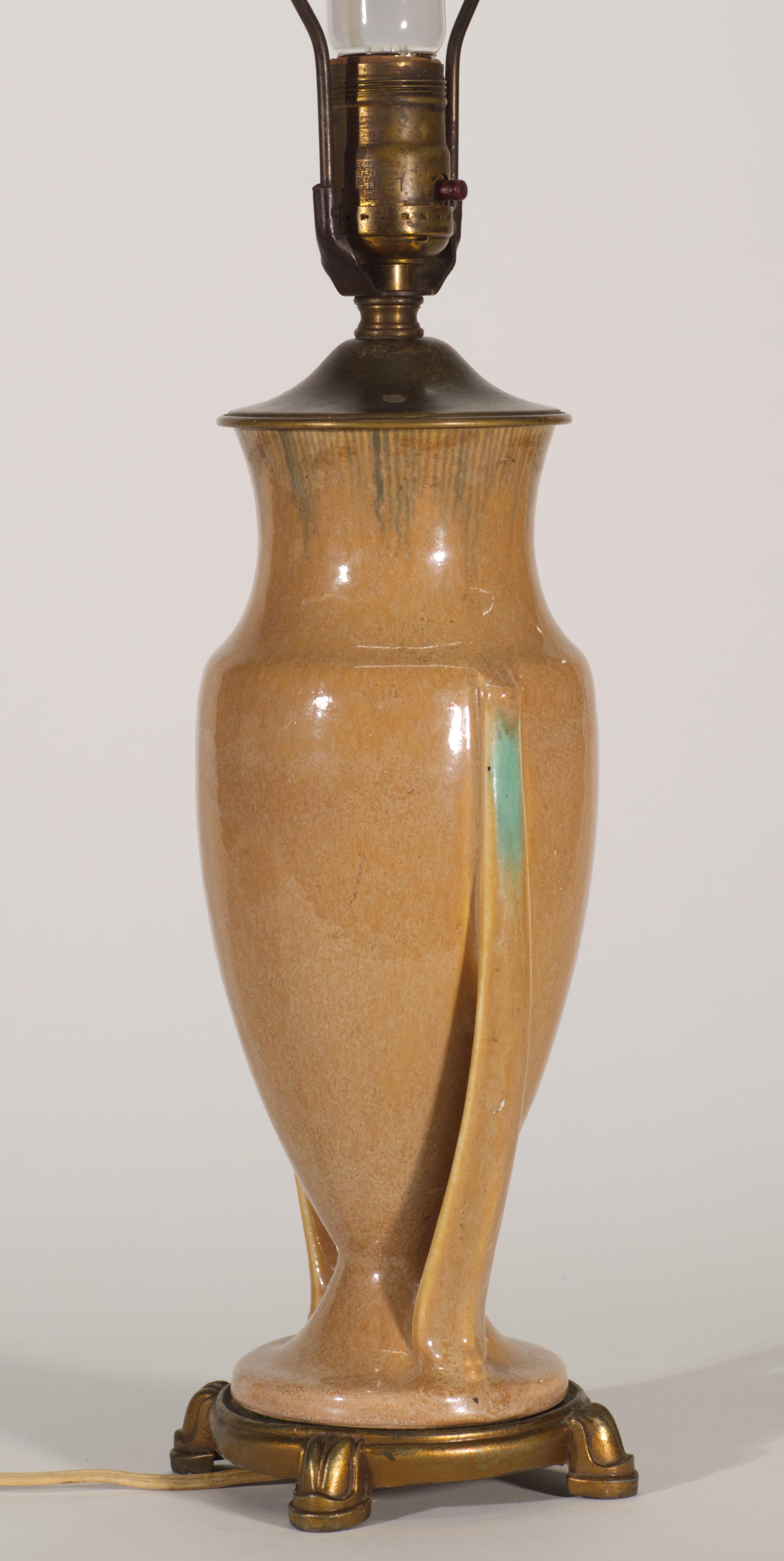 Cette lampe vintage de Roseville Pottery présente une glaçure beige feu avec une bordure peinte à la main sur le haut du corps en céramique, exécutée sous forme d'une série de courtes lignes verticales bleu foncé. Les poignées sont colorées en bleu