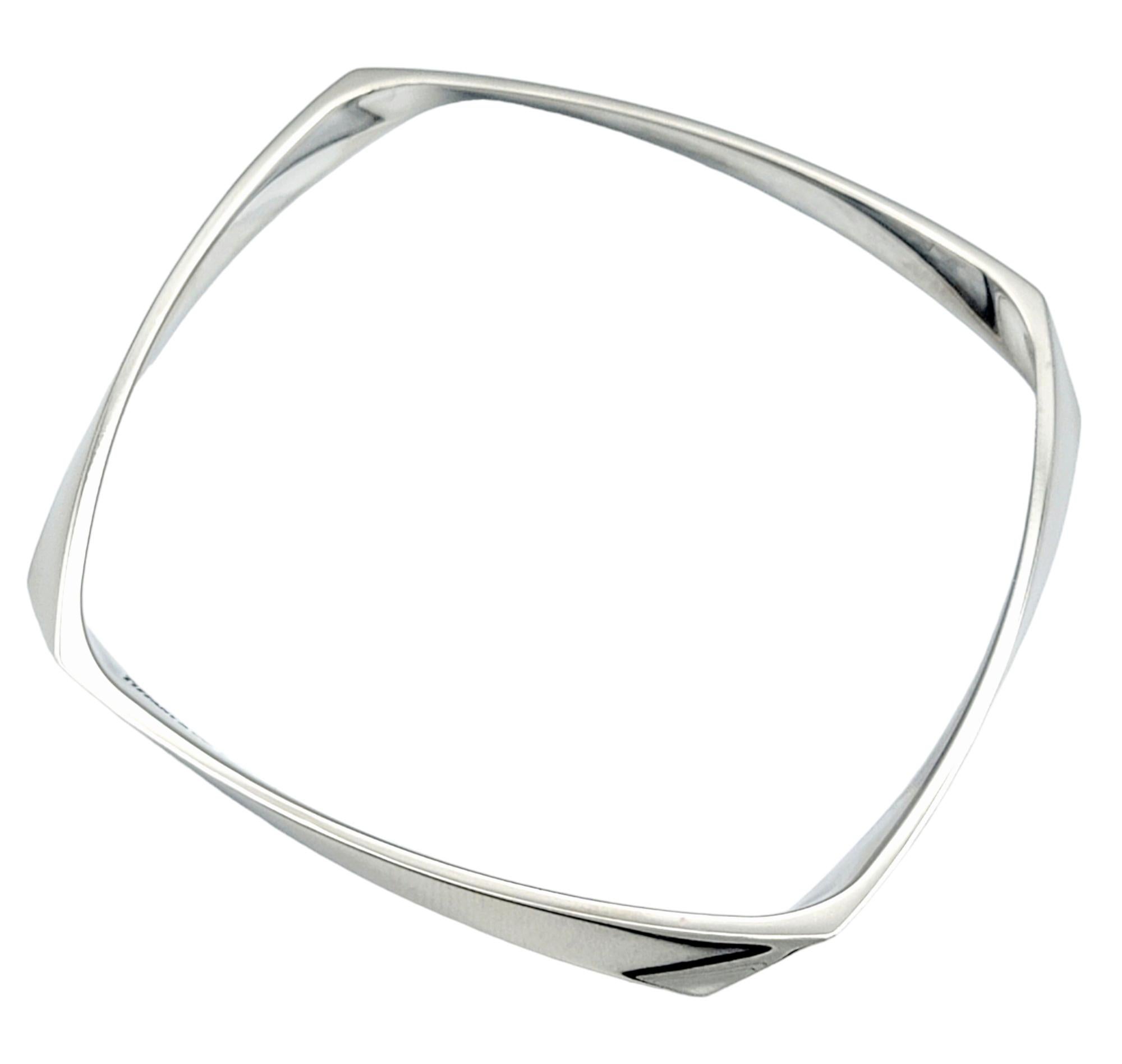 This Tiffany & Co. bracelet, designed by Frank Gehry and set in 18 karat white gold, showcases a unique and modern aesthetic. The squared bangle features an intriguing twist design, adding an element of dynamic movement to the piece. The absence of