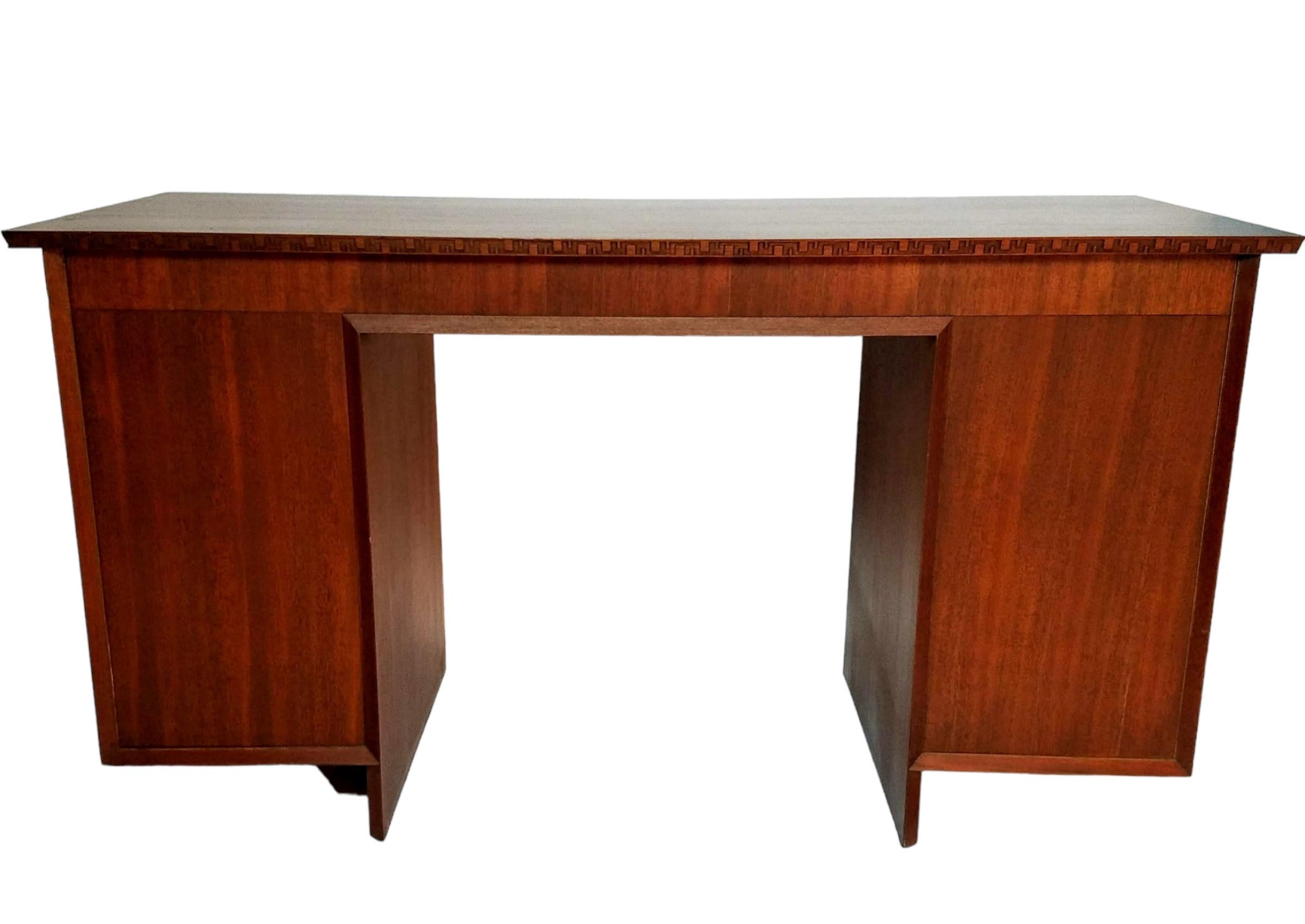 A classic nine drawer mahogany desk designed by Frank Lloyd Wright for his Taliesin line for Heritage Henredon furniture.
Beautifully detailed with a continuous incised carved greek key trim bordering the under edge of the top and the edges of the