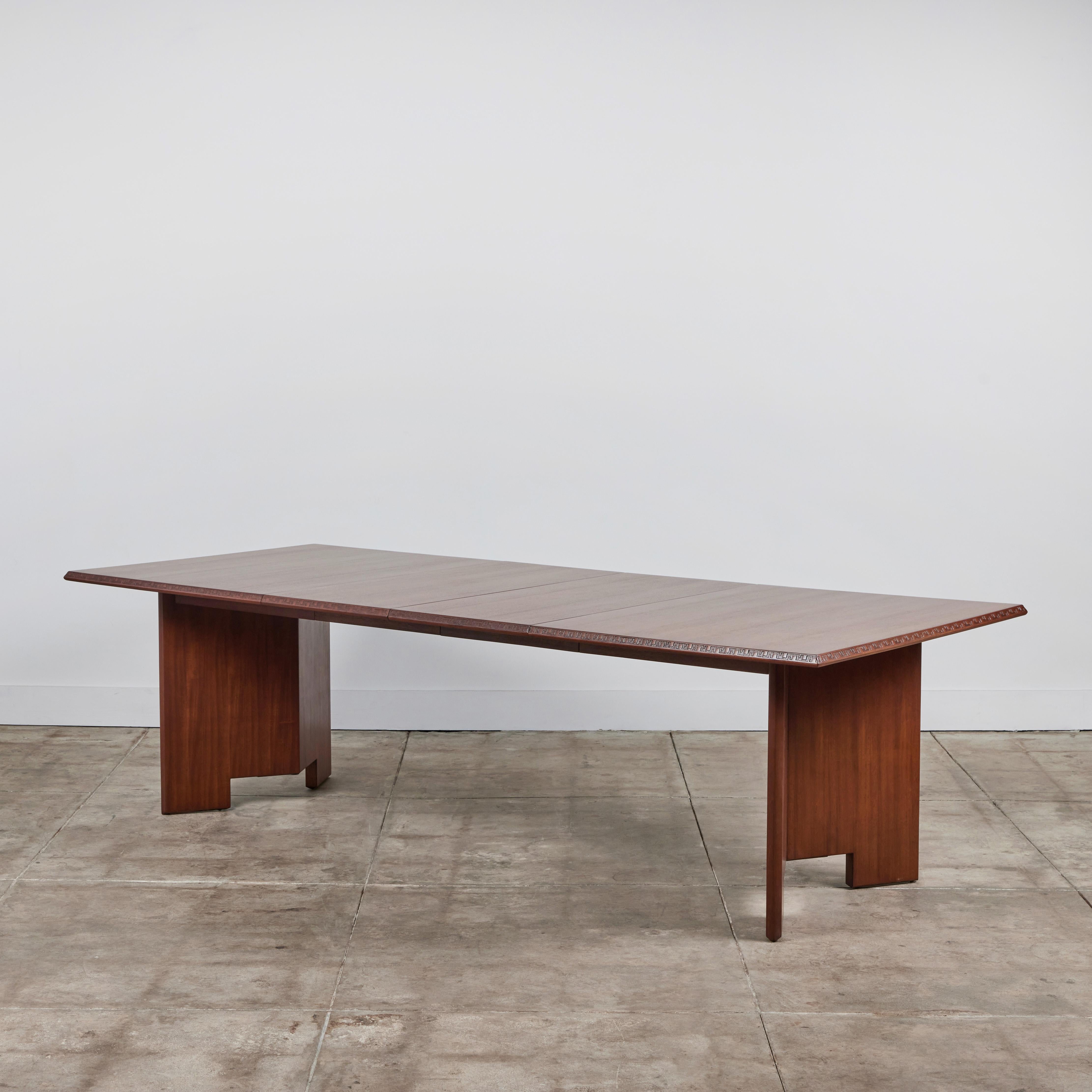 Rectangular dining table in Honduran mahogany designed by Frank Lloyd Wright for Heritage-Henredon in 1955. The beveled edge of the dining table is graced the Taliesin signature: an engraved Greek key motif. Two V-shaped segments form the legs of