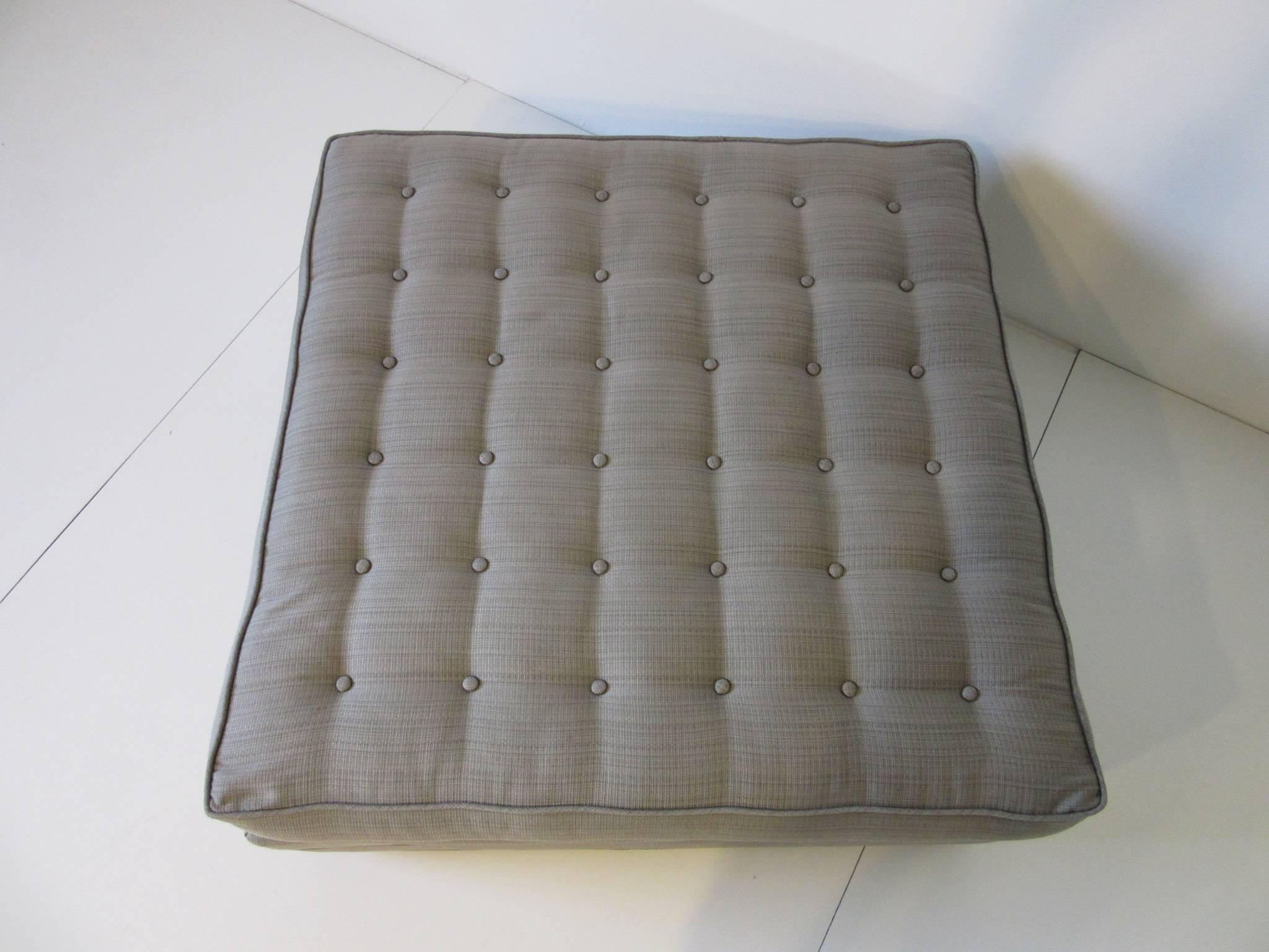An upholstered button tufted rolling ottoman or footstool manufactured by the Heritage Henredon furniture company for the Taliesin collection.