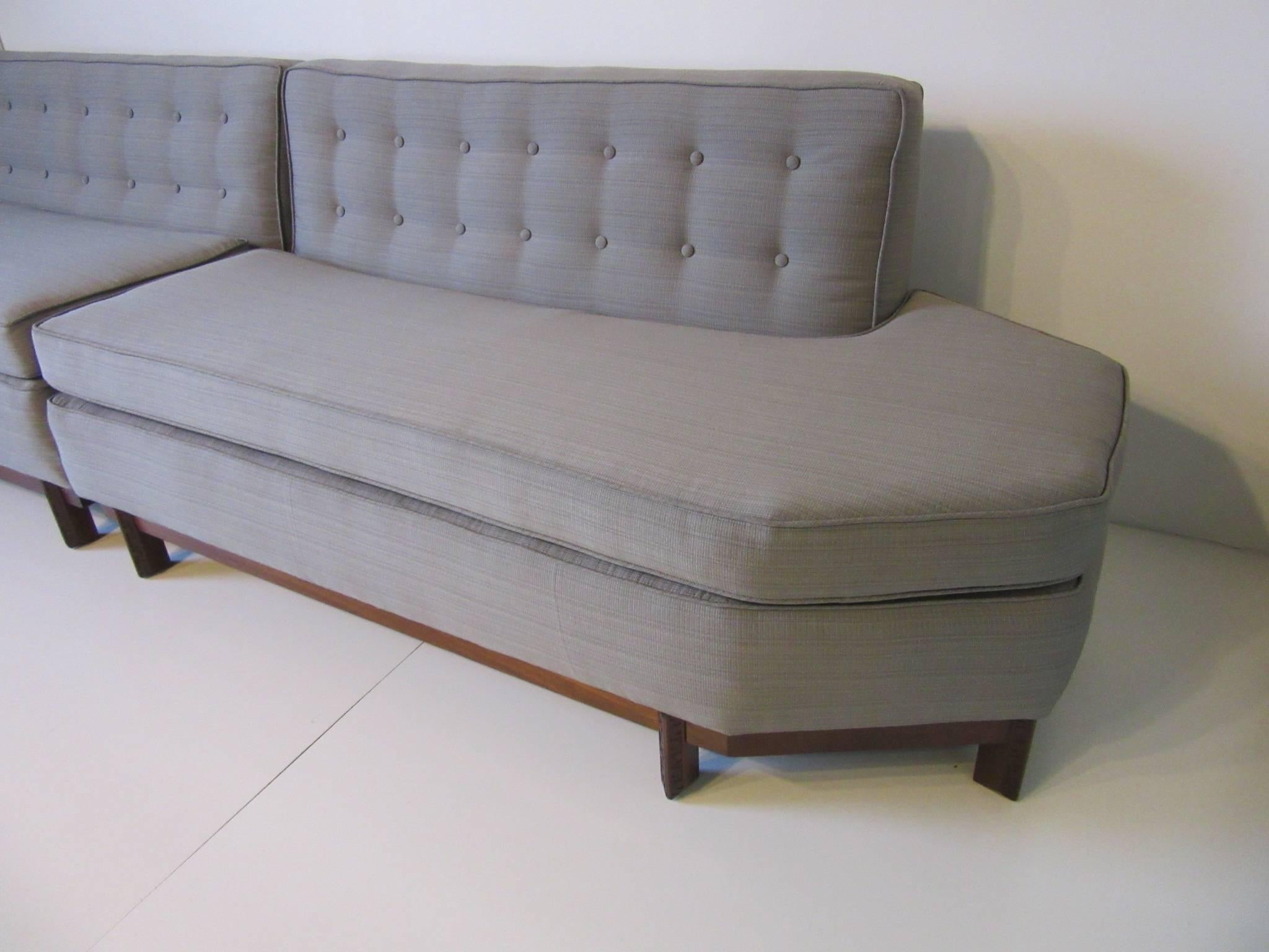 A two-piece sectional sofa designed by Frank Lloyd Wright with his trade mark Taliesin carved legs and walnut stretchers. The sofa has been newly reupholstered in a close to original fabric showing off the detailed octagon ends and button down