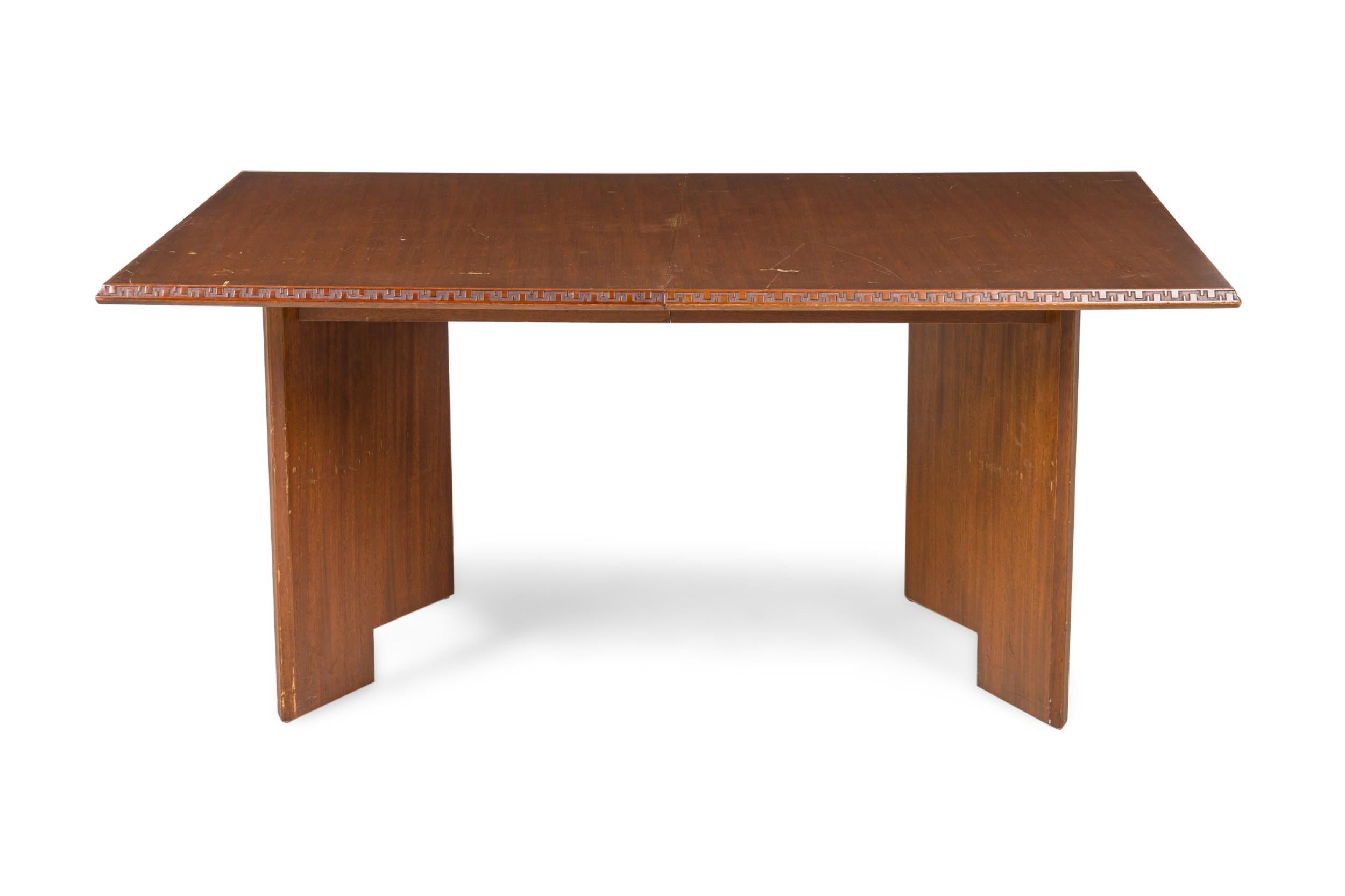 Table de salle à manger à rallonge en acajou américain du milieu du siècle dernier avec  garniture à motif géométrique en touches, avec deux feuilles amovibles, reposant sur de larges pieds en planches. (FRANK LLOYD WRIGHT- Collection