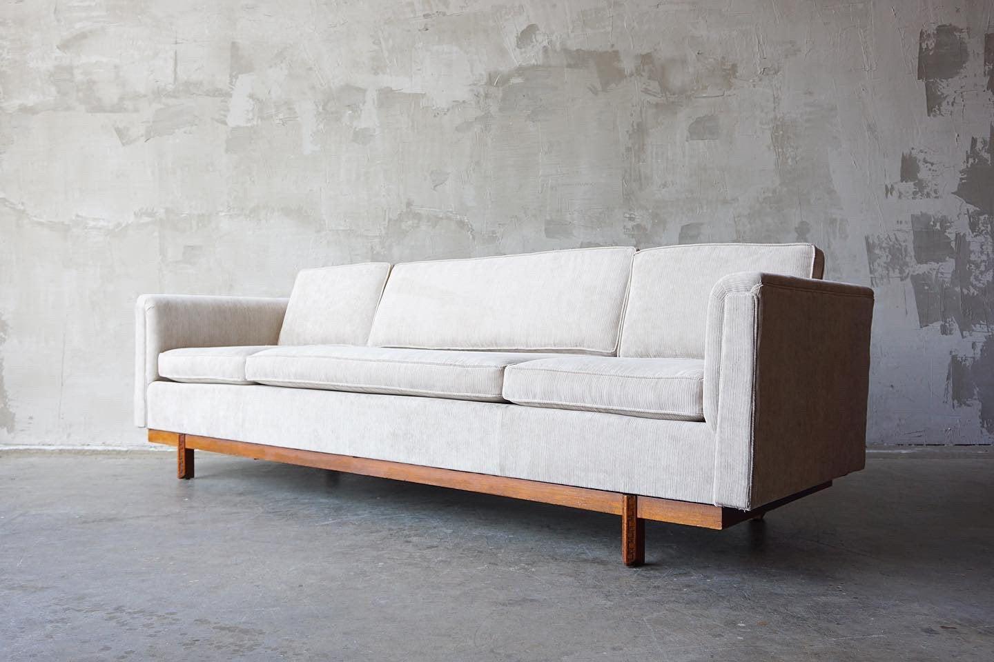 Clean and quiet lined sofa designed by Frank Lloyd Wright for Henredons ‘Taliesen’ line. 

Featuring a solid mahogany detailed frame in very nice original condition with new warm grey pleated cotton velvet upholstery. 

Measures 99” W x 33.5” D