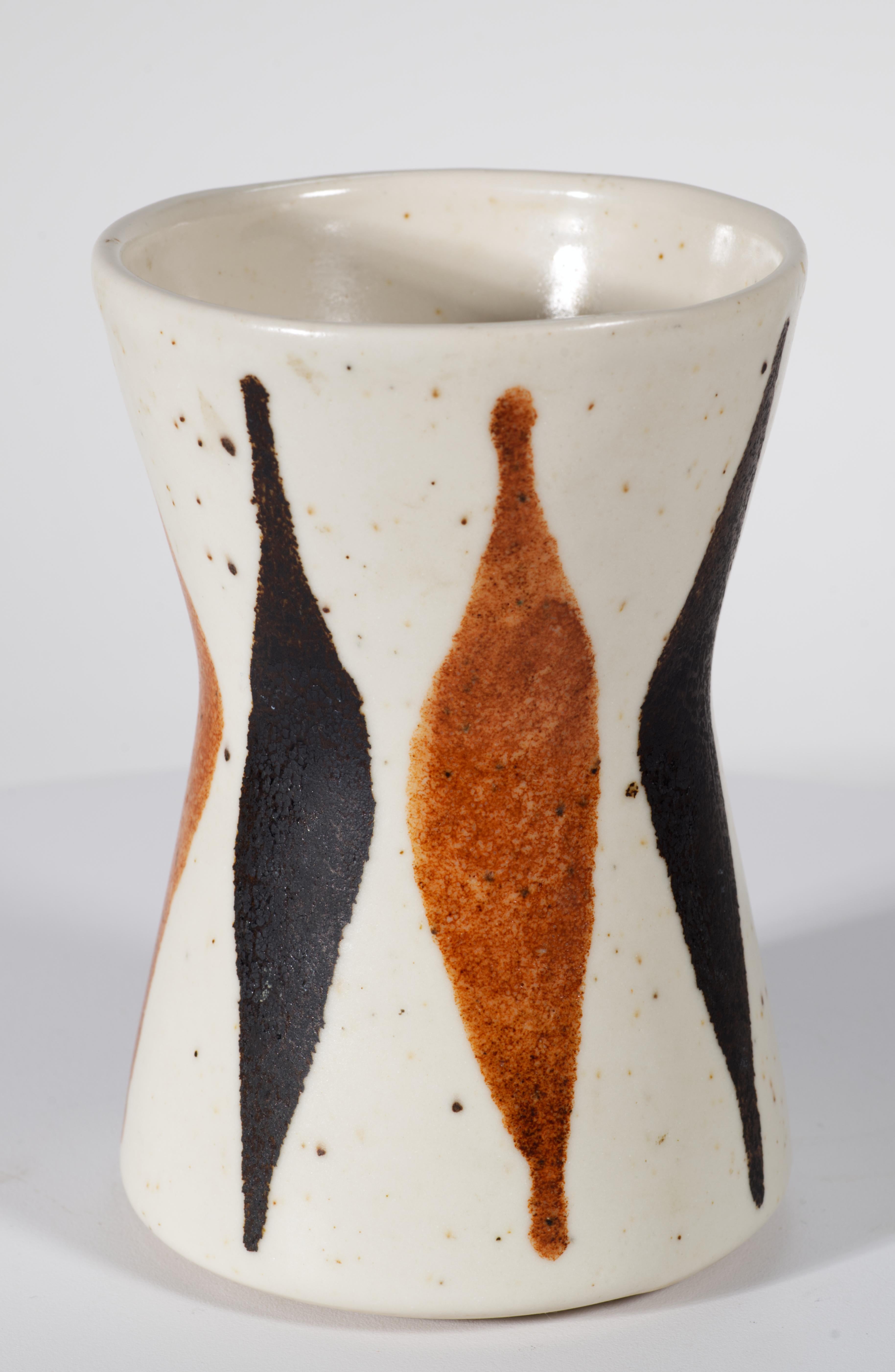  Il vaso in ceramica del Mid Century Modern presenta un disegno grafico astratto con forme alternate di colore marrone e nero su uno sfondo bianco sporco e screziato. Il decoro audace ma organico completa la forma a clessidra del vaso, con le parti