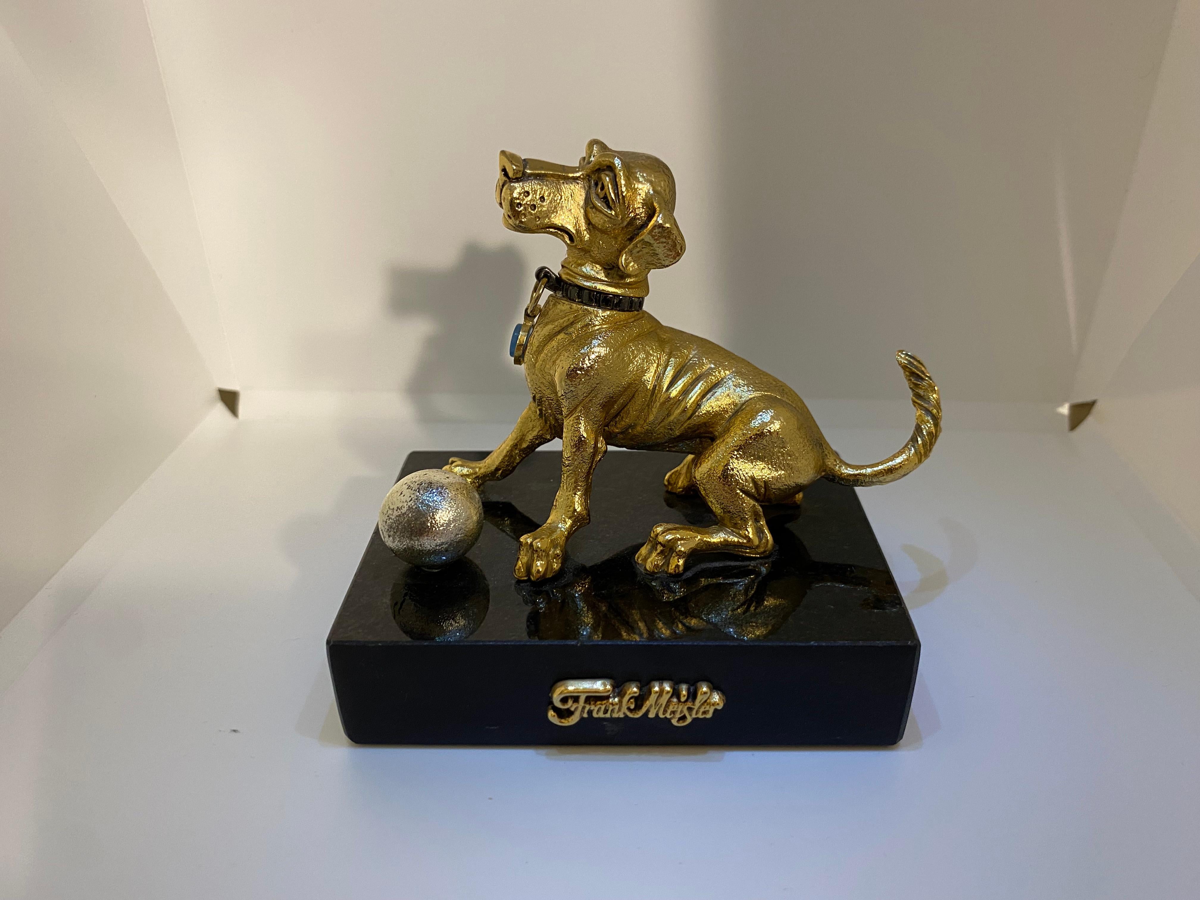 FRANK MEISLER MINI GOLD DOG
H9 x W9 x L6 cm – 560g
The dog is sitting with a ball. The dog’s head turns sideways. Handmade. Limited Edition. Metal Alloys with gold and silver plated elements. 
