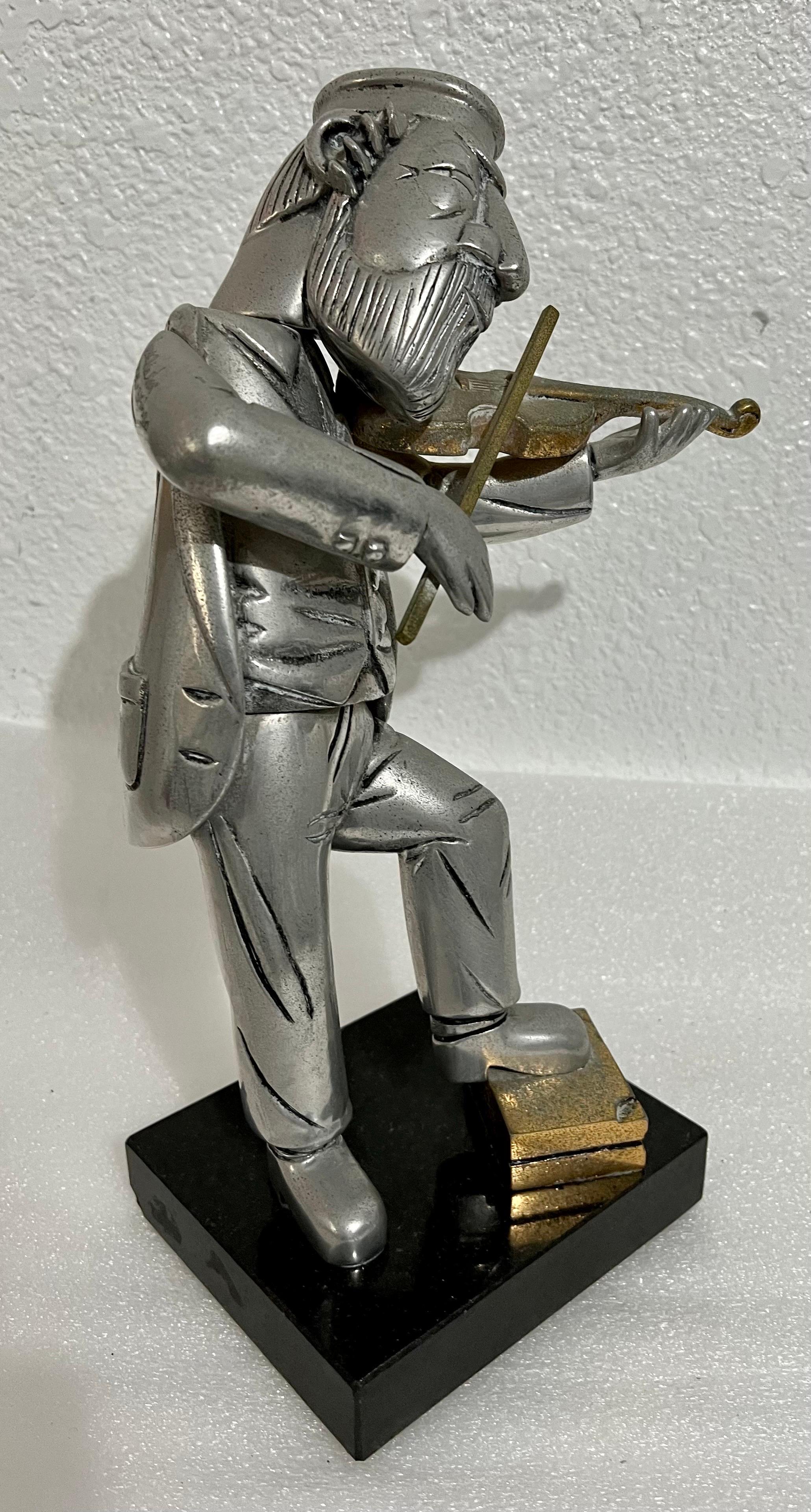 Rare Vintage unusual piece.
In this bronze or metal sculpture by Frank Meisler, the artist depicts a Klezmer violin player The figure seems cartoon-like with exaggerated facial features.

FRANK MEISLER
Gdansk, Poland - Israel, b. 1929
Frank Meisler