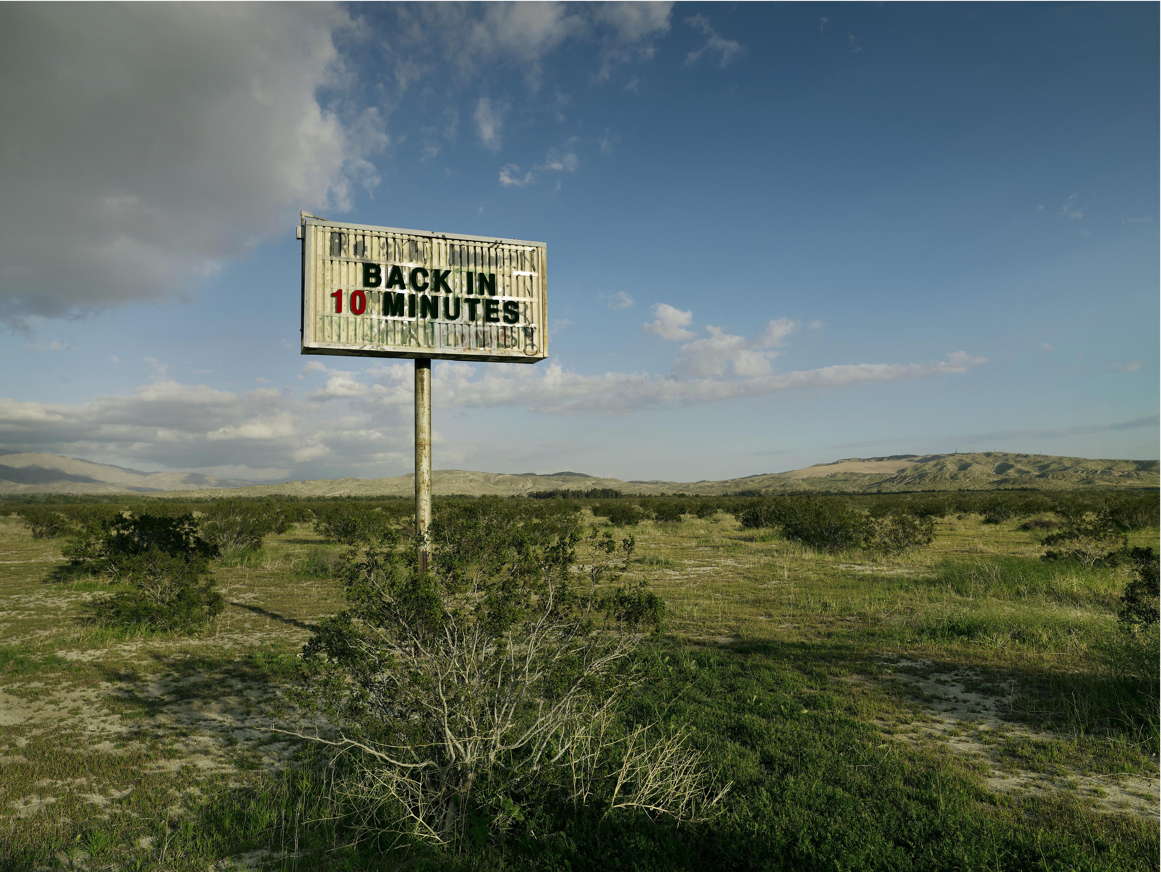 Frank Schott Landscape Print - Back in 10 - large format photograph of conceptual message sign in landscape