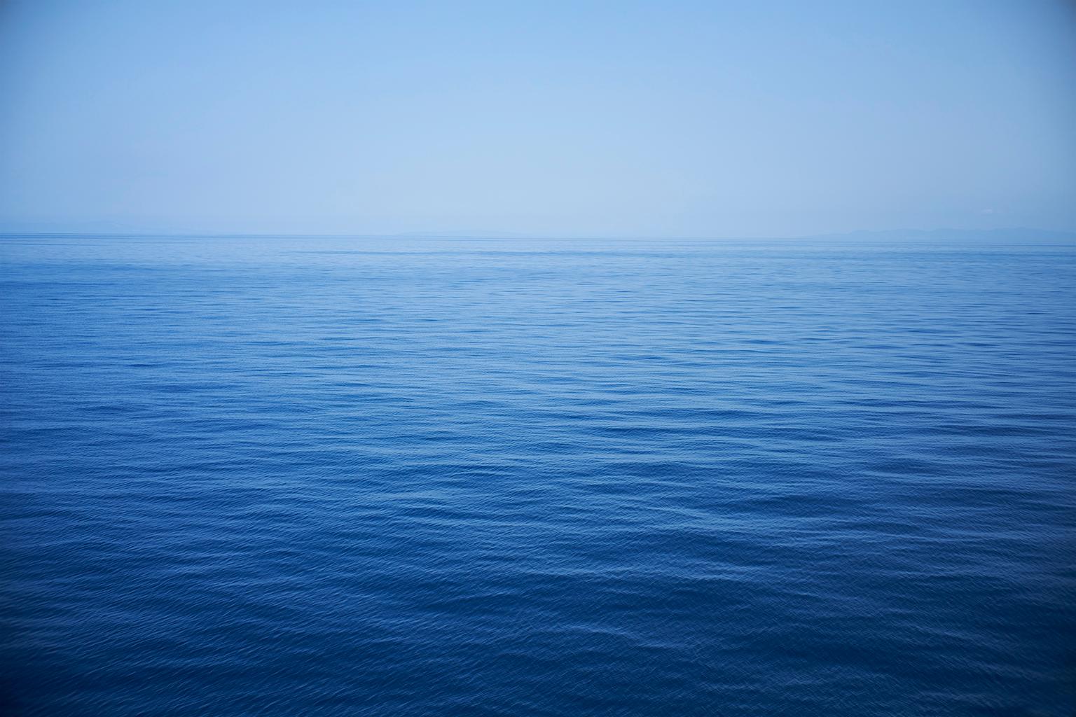 Frank Schott Color Photograph – Meereslandschaft X – Großformatfotografie mit monochromer blauer Wasseroberfläche und Horizont