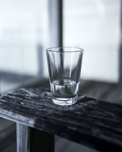 Nature morte avec de l'eau - vignette monochrome représentant un verre transparent rempli d'eau posé sur une table