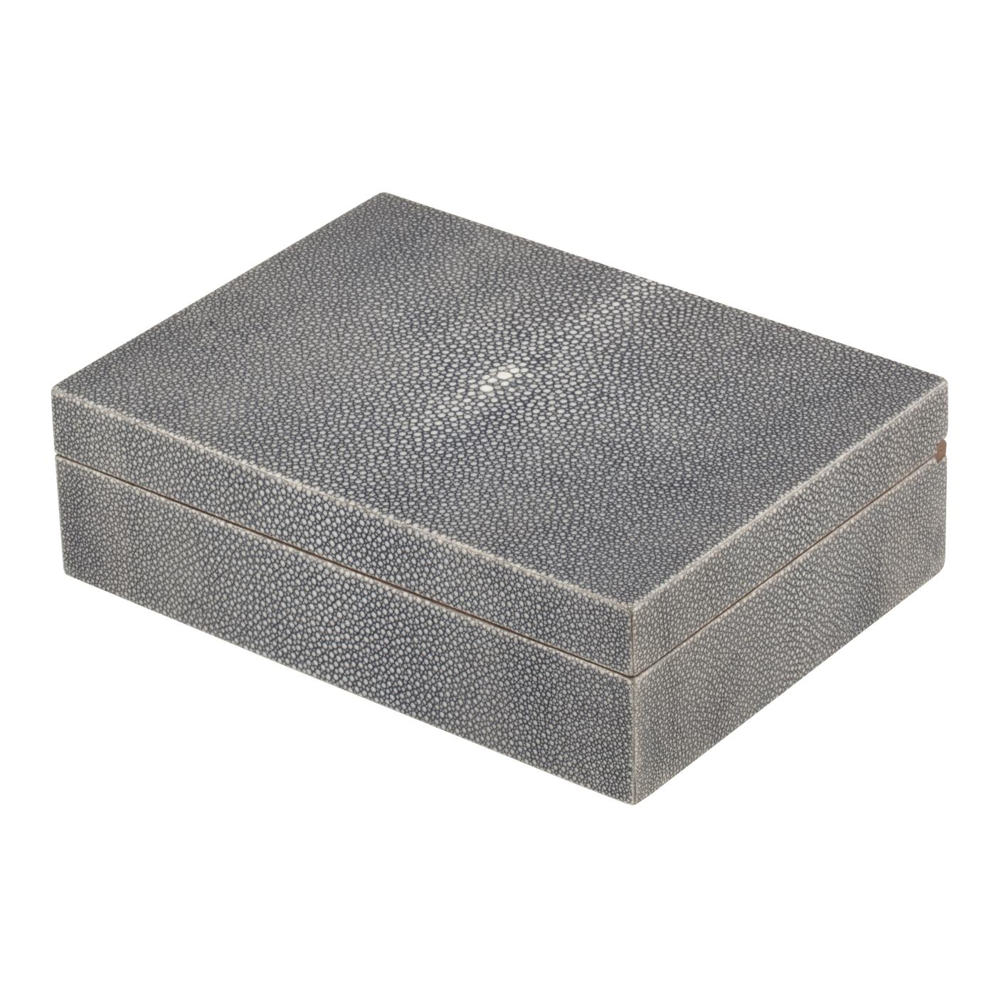 Cette boîte exquise est entièrement réalisée en bois de noyer dont les charnières sont également façonnées dans le même matériau. Les surfaces extérieures sont recouvertes d'un véritable cuir de galuchat qui ajoute une touche luxueuse à sa texture.