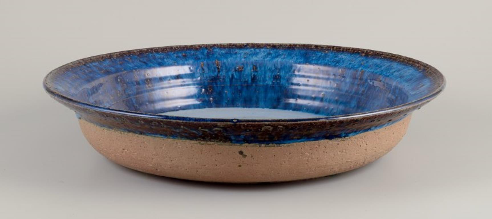 Frank Tromborg (b. 1937), Danish ceramist. Own workshop.
Colossal unique ceramic bowl.
Glaze in bluish hues.
Partially unglazed.
Signed and dated 71 (1971).
In perfect condition.
Dimensions: D 43.5 cm x H 8.5 cm.