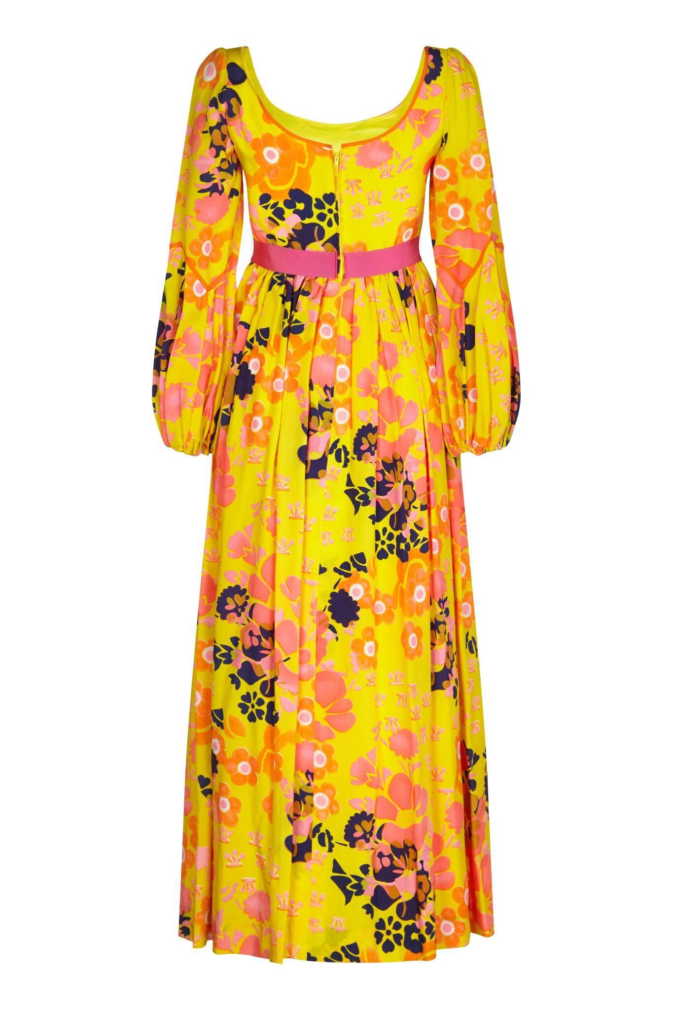 Cette robe à imprimé floral jaune psychédélique des années 1960 de Frank Usher, avec des détails en ruban rose, est une pièce magnifiquement construite. Le généreux cachet de soie est à dominante jaune soleil avec un saisissant motif floral