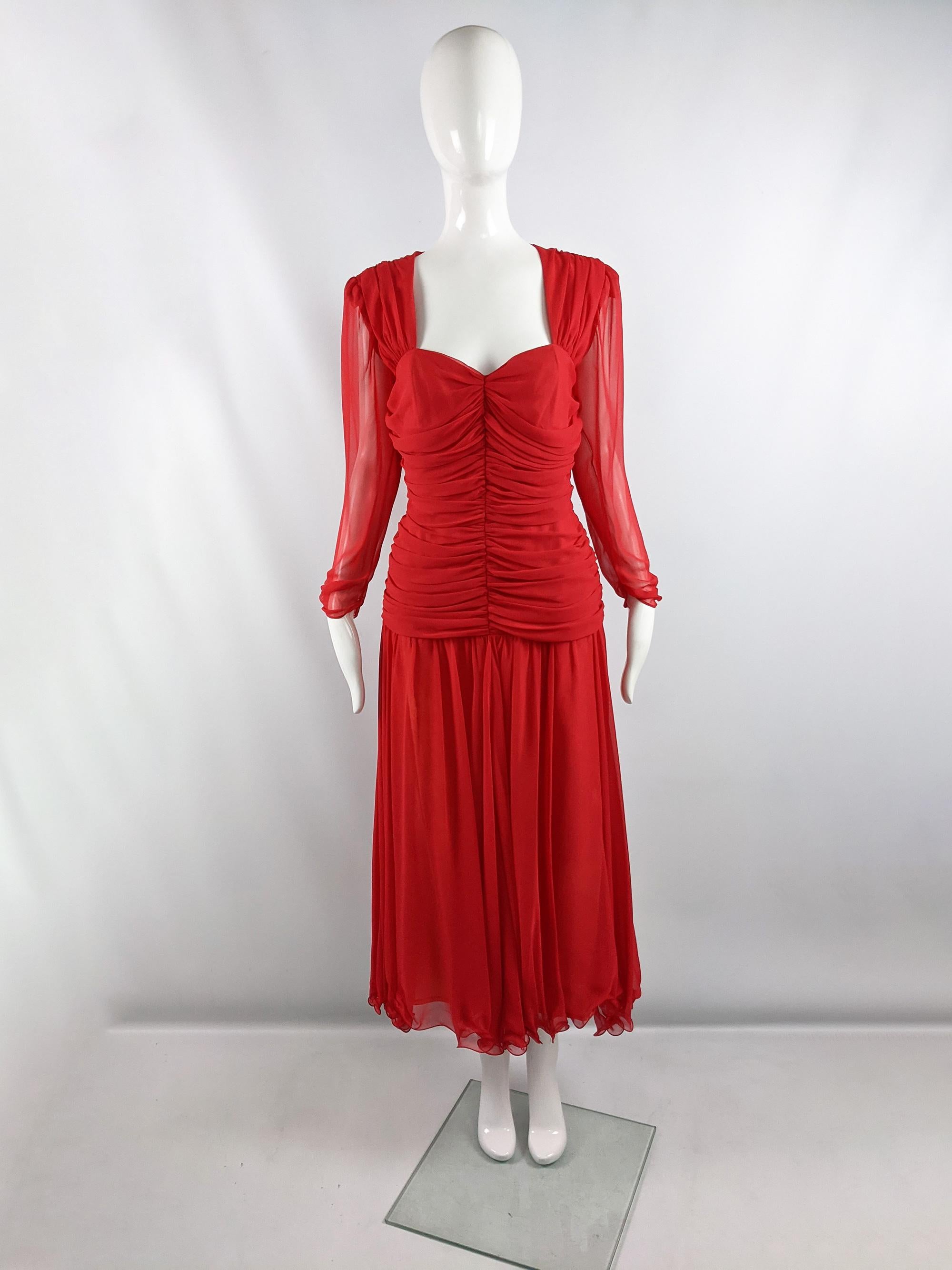 A fabulous vintage Frank Usher evening dress from the 80s. In a red chiffon with a ruched, drop waisted body and a long floaty skirt. The sleeves and back are sheer and the bust has a sweetheart neckline, adding loads of sex appeal.

Size: Marked