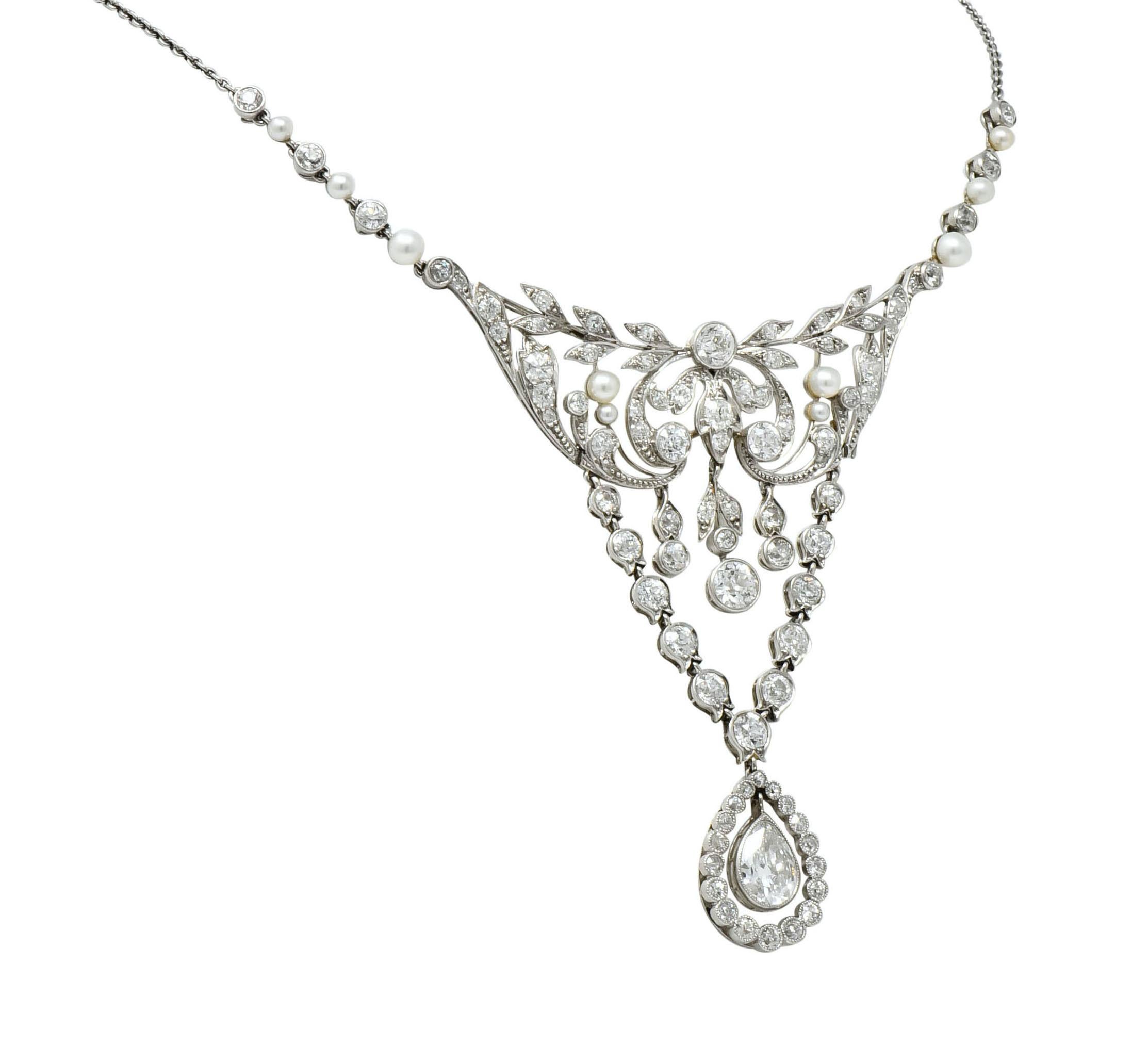 Centering a large station comprised of a scrolled foliate design with two extensions of tulip motif links terminating in a pear shaped articulated drop

Terminating in a pear shaped articulated drop, bezel set, with a pear cut diamond weighing