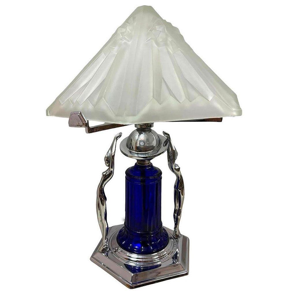 Magnifique lampe de dame chromée de style Art Déco avec lourd abat-jour en verre dépoli. Il y a deux sculptures de femmes nues le long de la base et un abat-jour en verre bleu cobalt monté sur une base chromée à gradins. Le dessus présente un grand