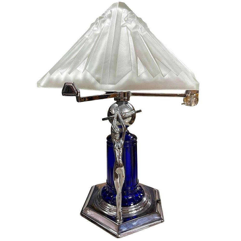 Magnifique lampe de dame chromée de style Art Déco avec lourd abat-jour en verre dépoli. Il y a deux sculptures de femmes nues le long de la base et un abat-jour en verre bleu cobalt monté sur une base chromée à gradins. Le dessus présente un grand
