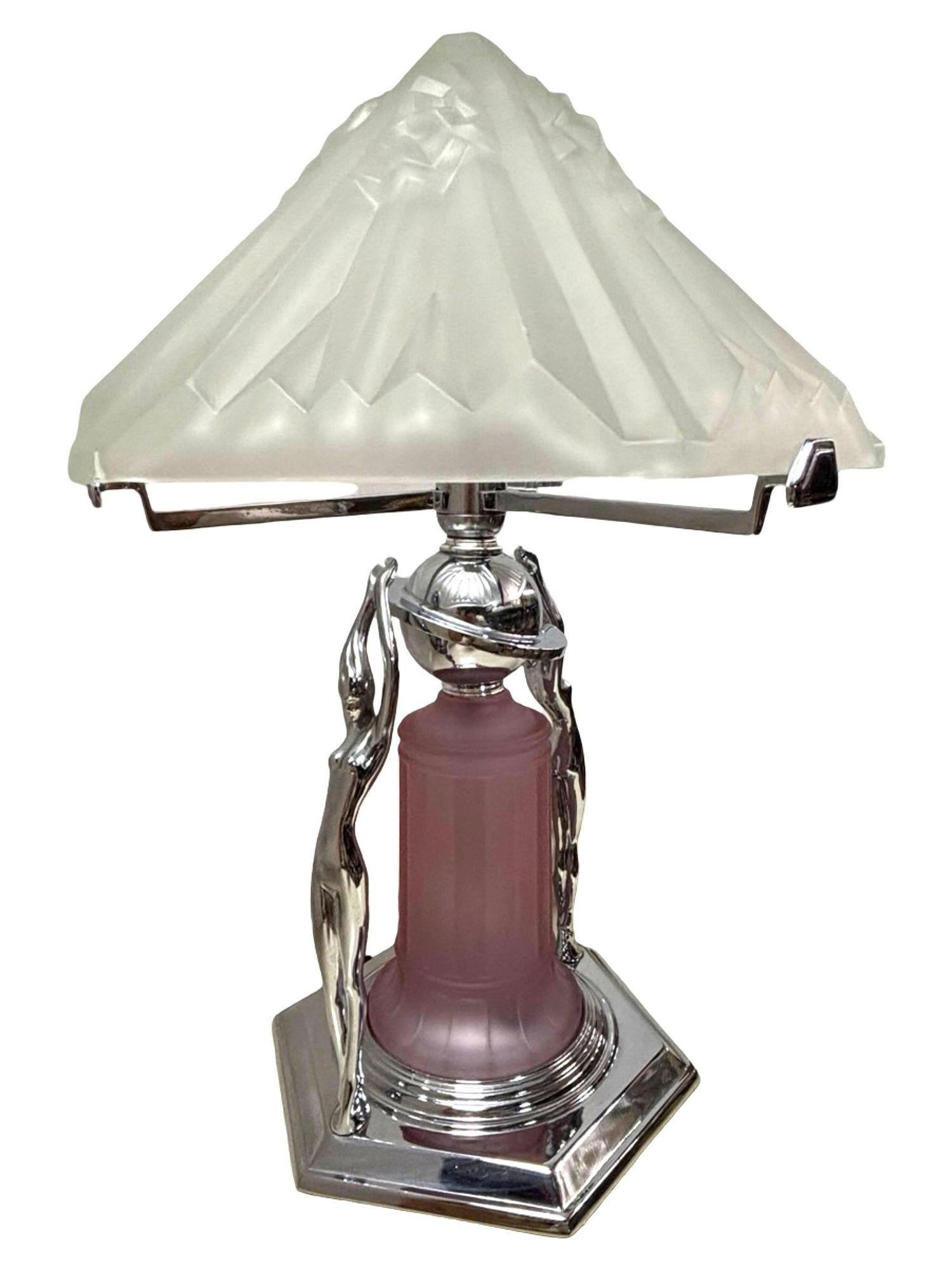 Magnifique lampe de dame chromée de style Art Déco avec un lourd abat-jour en verre dépoli, présentant deux sculptures de femmes nues le long de la base avec un abat-jour en verre rose Vivian, le tout monté sur une base chromée à gradins. Le dessus
