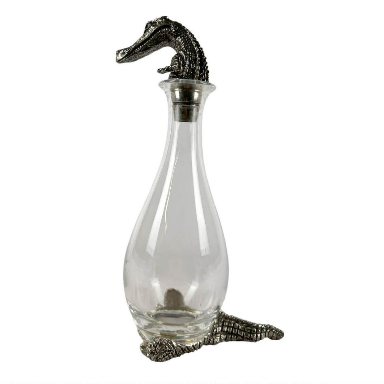 Whimsically modeled mixed media glass and metal bar barware themed article designed in the form of a crocodile alligator from the South African company Frankli Wild. The decanter is mouth blown crystal from France, the pewter head, feet and tail