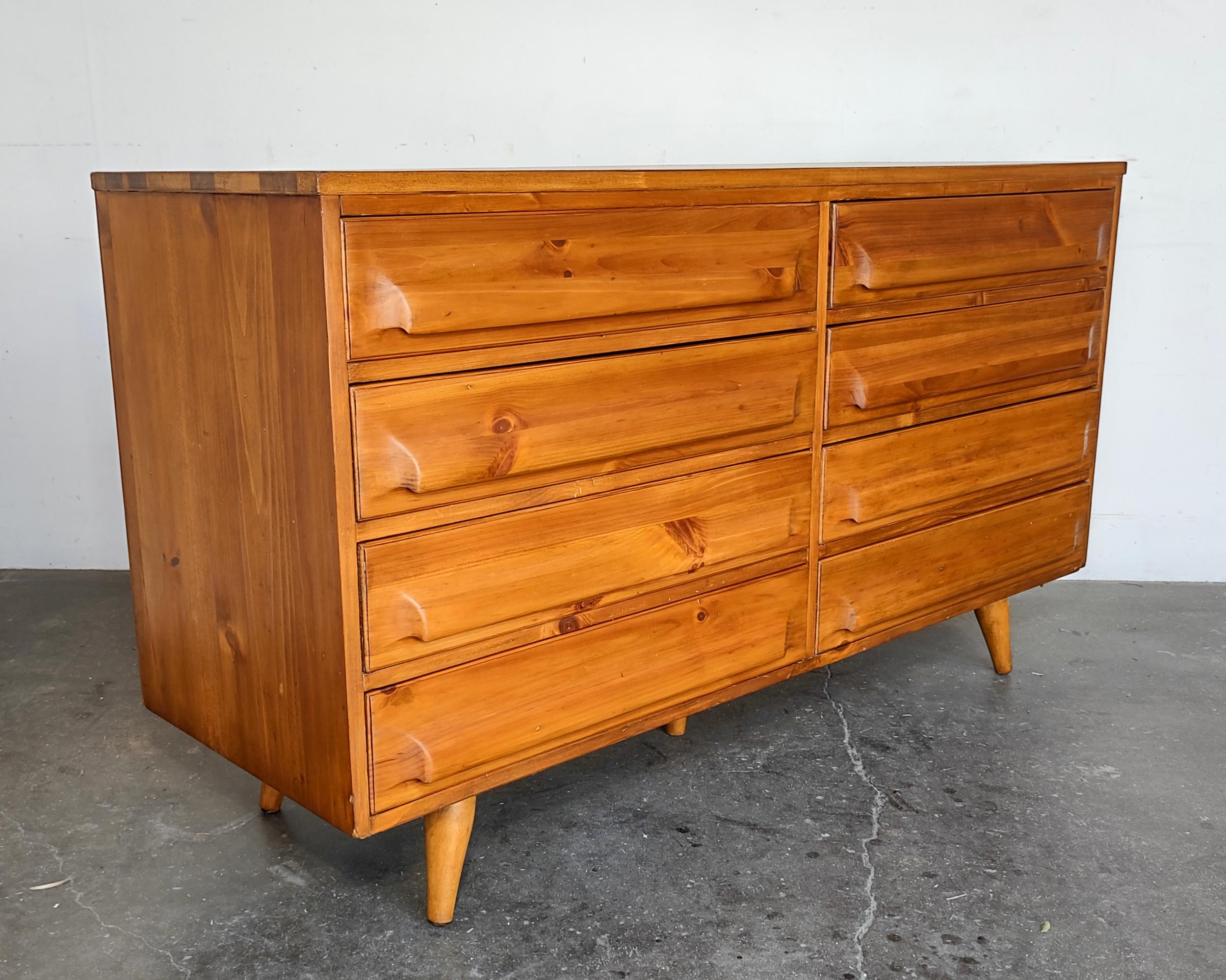 Fully refinished hand-burnished pine lowboy dresser with eight mahogany-lined drawers and dovetail joinery. Drawer faces and legs are sculpted from solid pine and the case is solid wood construction with pine veneer. Overall excellent vintage