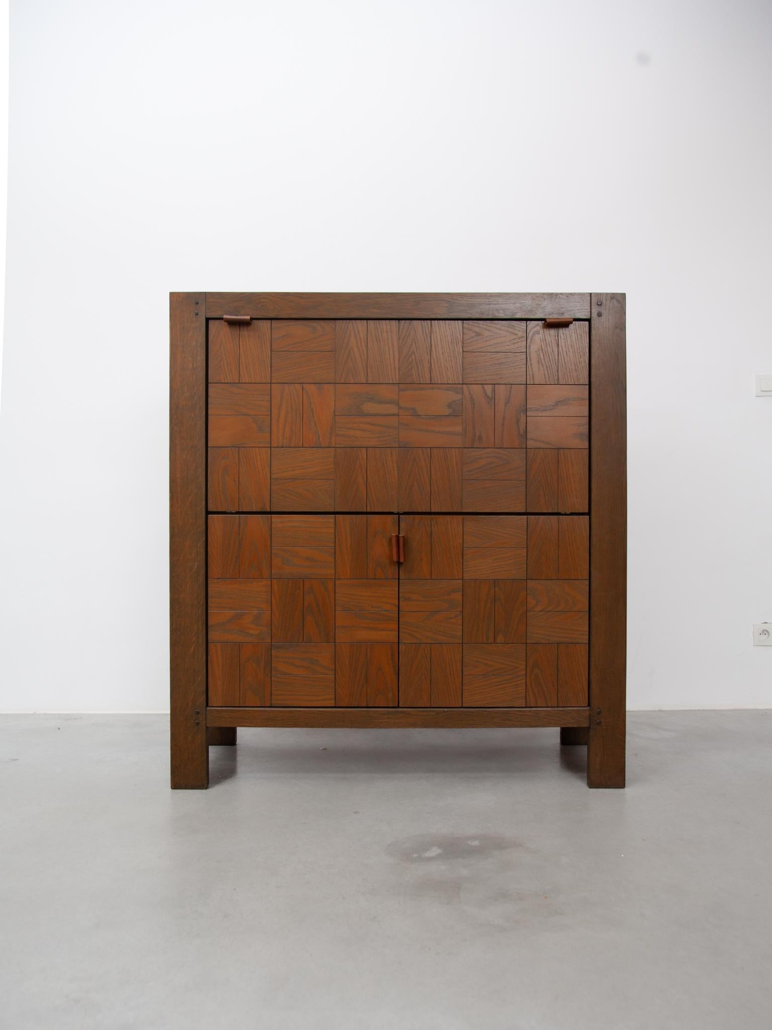 Buffet haut moderniste vintage en bois incrusté de carreaux de chêne grainé, conçu par Frans Defour pour Defour, années 1970,
Belgique Design/One. Ce très rare buffet de bar est en bon état d'origine avec un joli détail de poignées en cuir.
 